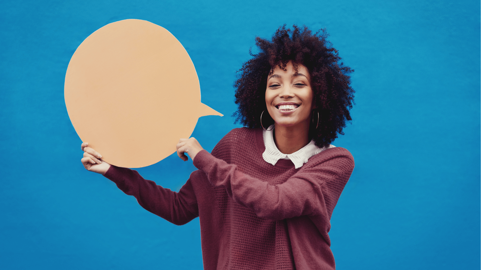 A young woman holding a speech bubble-shaped sign