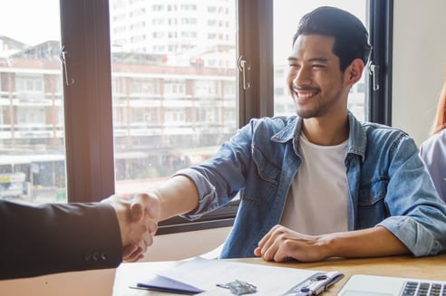 two men shaking hands in front of a city skyline.