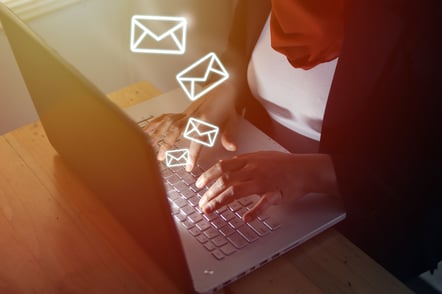 hands typing on a laptop with neon envelopes trailing from the laptop