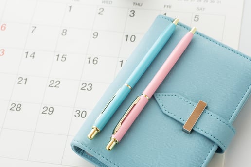 blue planner laying on top of a flat paper calendar