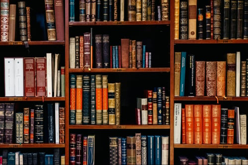 A large bookshelf full of antique books 