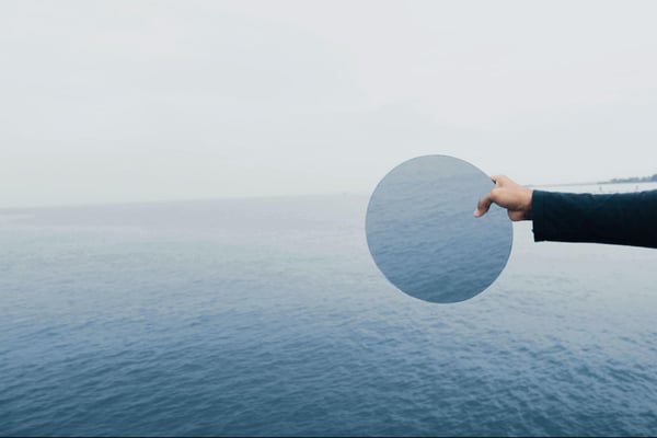 A circular mirror reflecting the ocean