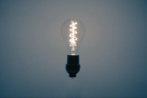  a lit lightbulb against a grey background