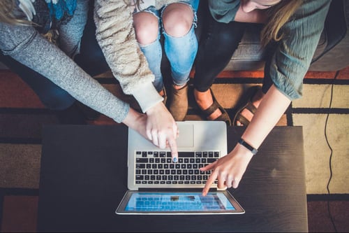 Three people pointing at a laptop screen