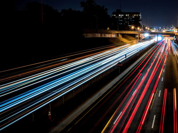 Cars speed past on a highway at night