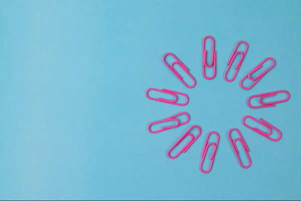 Pink paperclips form a circle against a light blue background