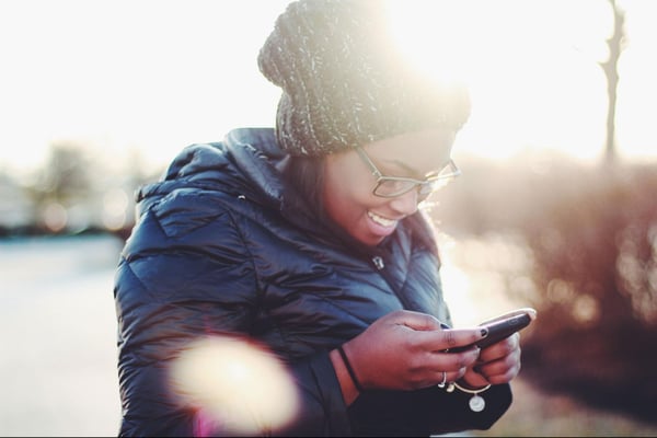 A person looks at their mobile phone and smiles