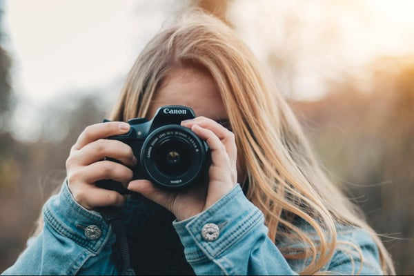 A person takes a picture with a Canon brand camera