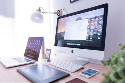 A desktop computer, a laptop, an e-reader, and a smartphone all on the same desk.