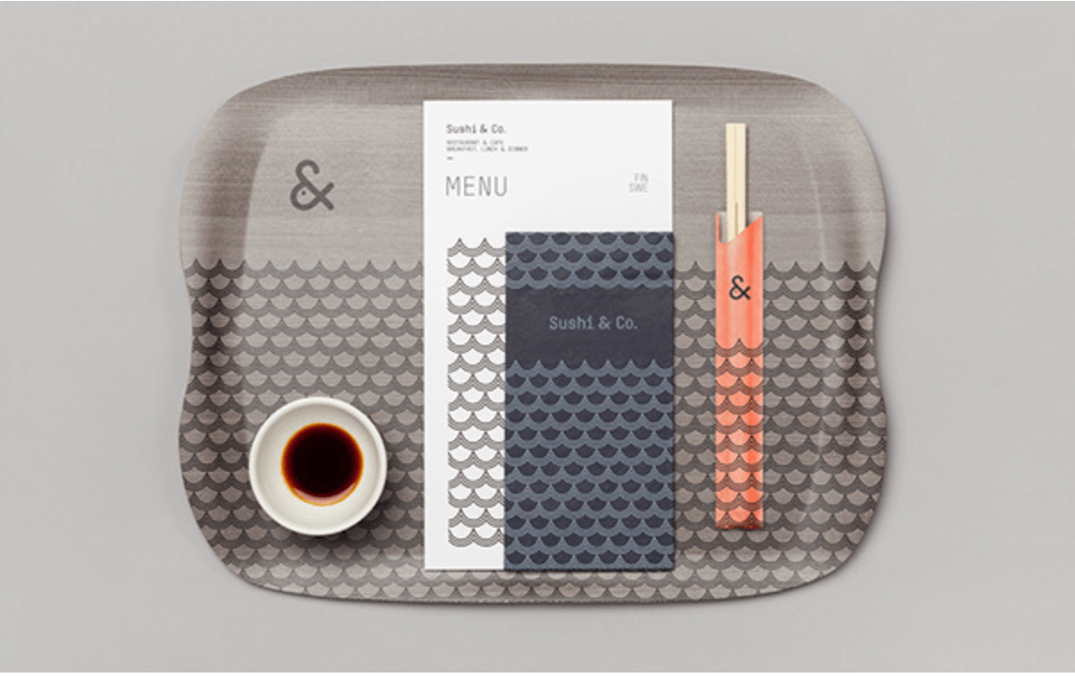 A tray, menu, and pair of chopsticks that demonstrate Sushi and Co's in-restaurant branding