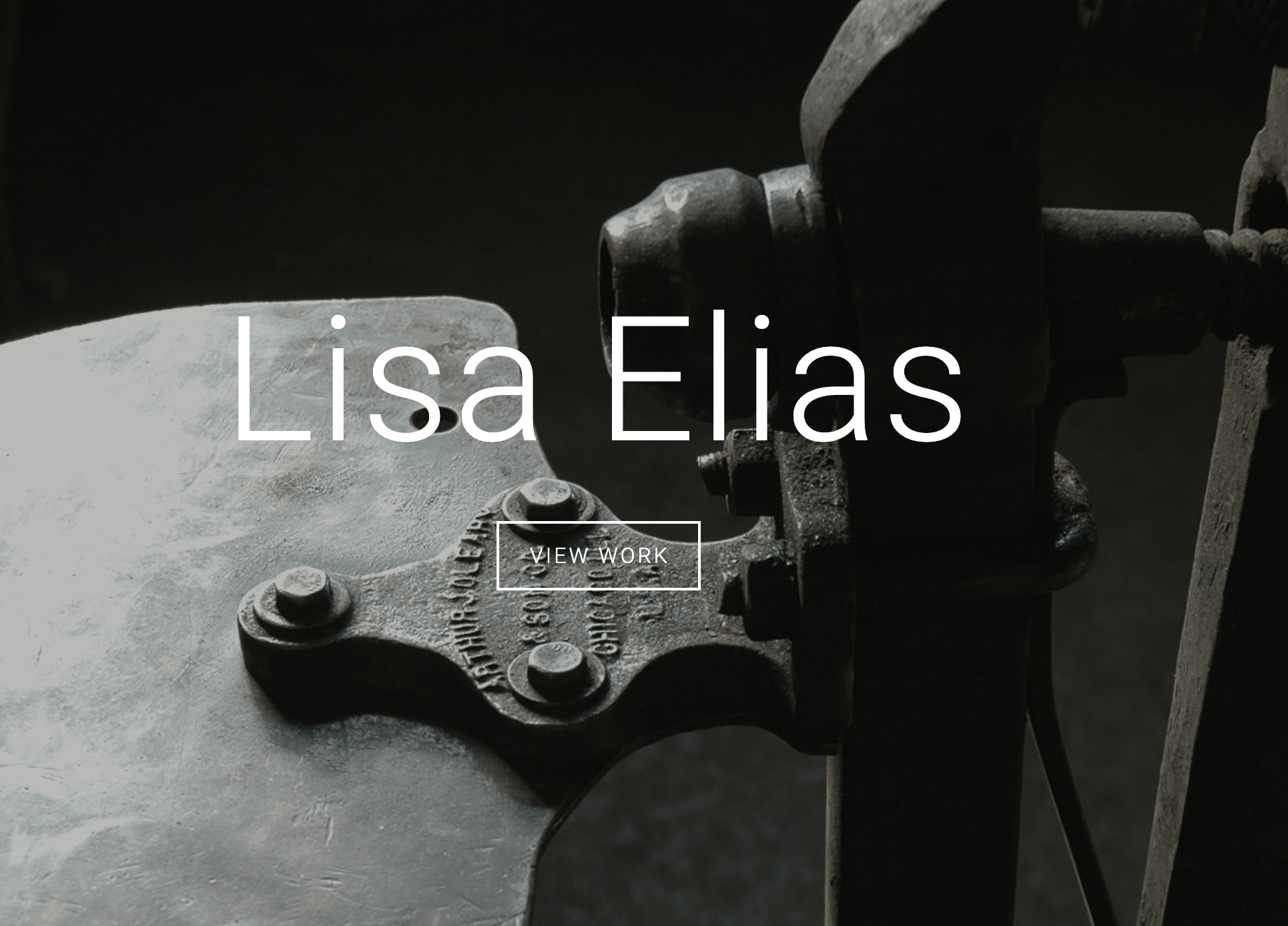 The home page for Lisa Elias' website featuring simply her name and a button that reads "view work" over a large black and white photo of her metal shop. 