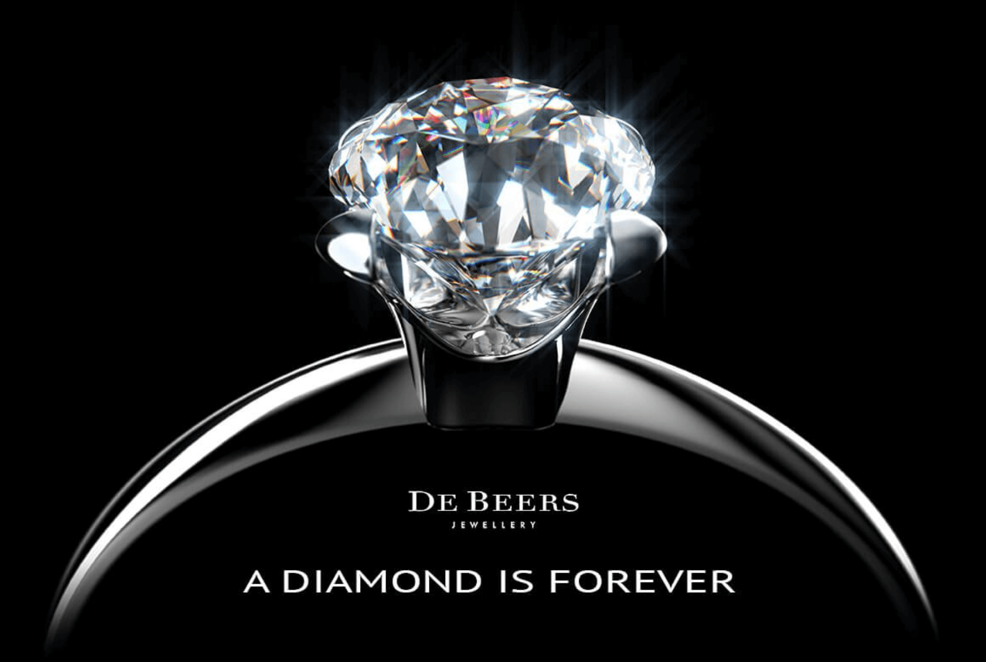 A closeup of a diamond ring with text that reads "De Beers Jewelry: A Diamond is Forever"