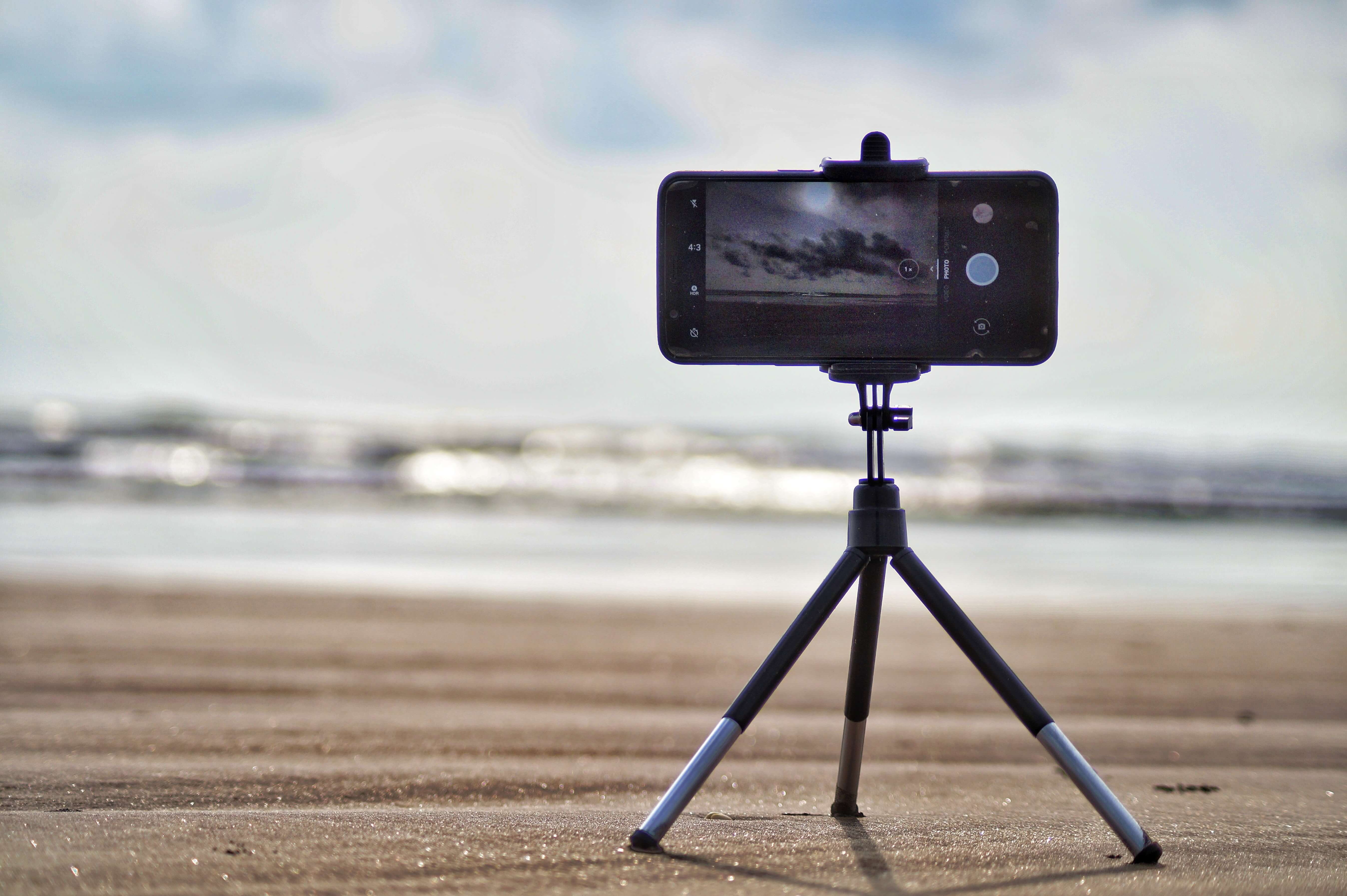 A smartphone on a tripod in landscape to take a photo of the beach. 