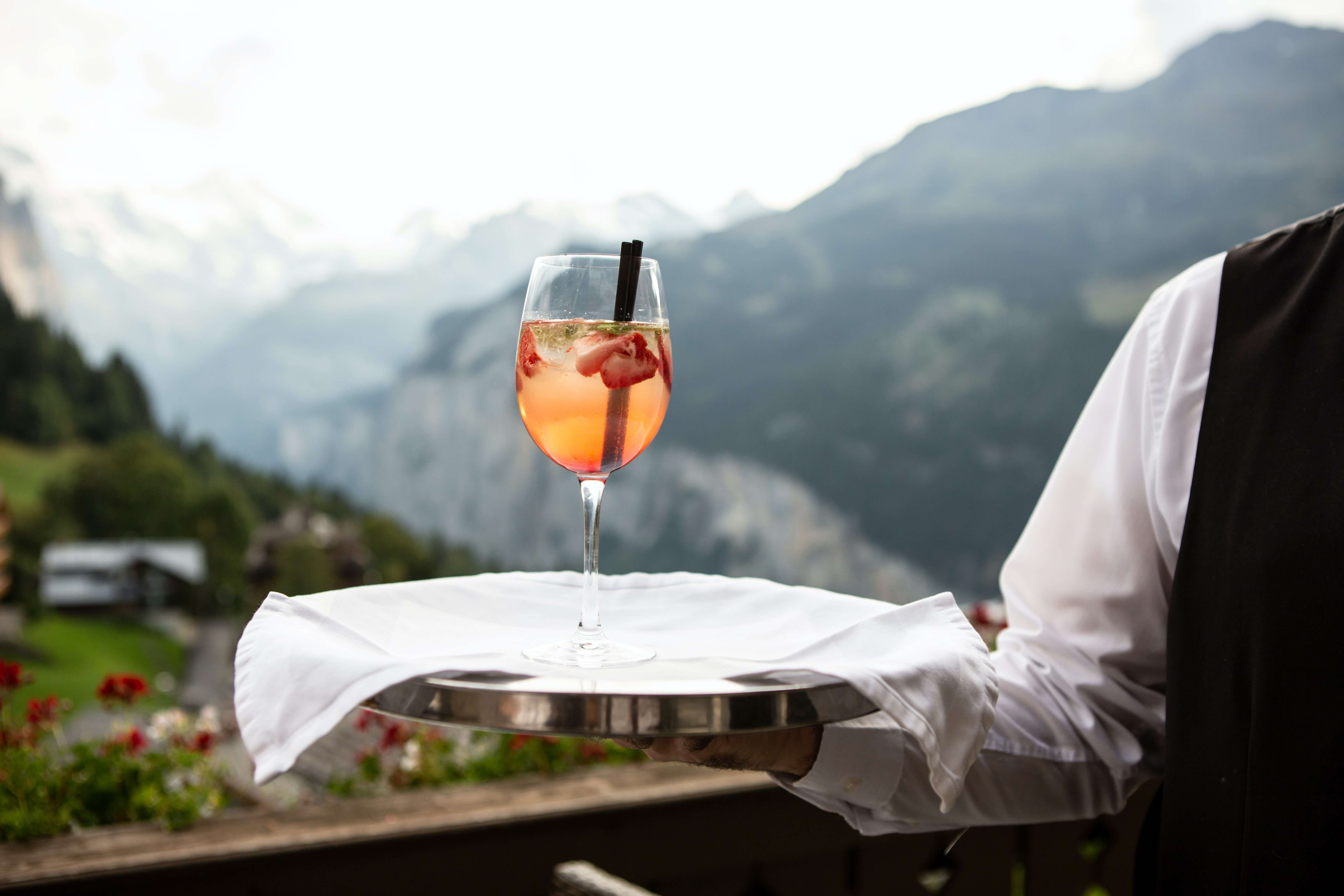 A waiter serving a glass of wine on a platter