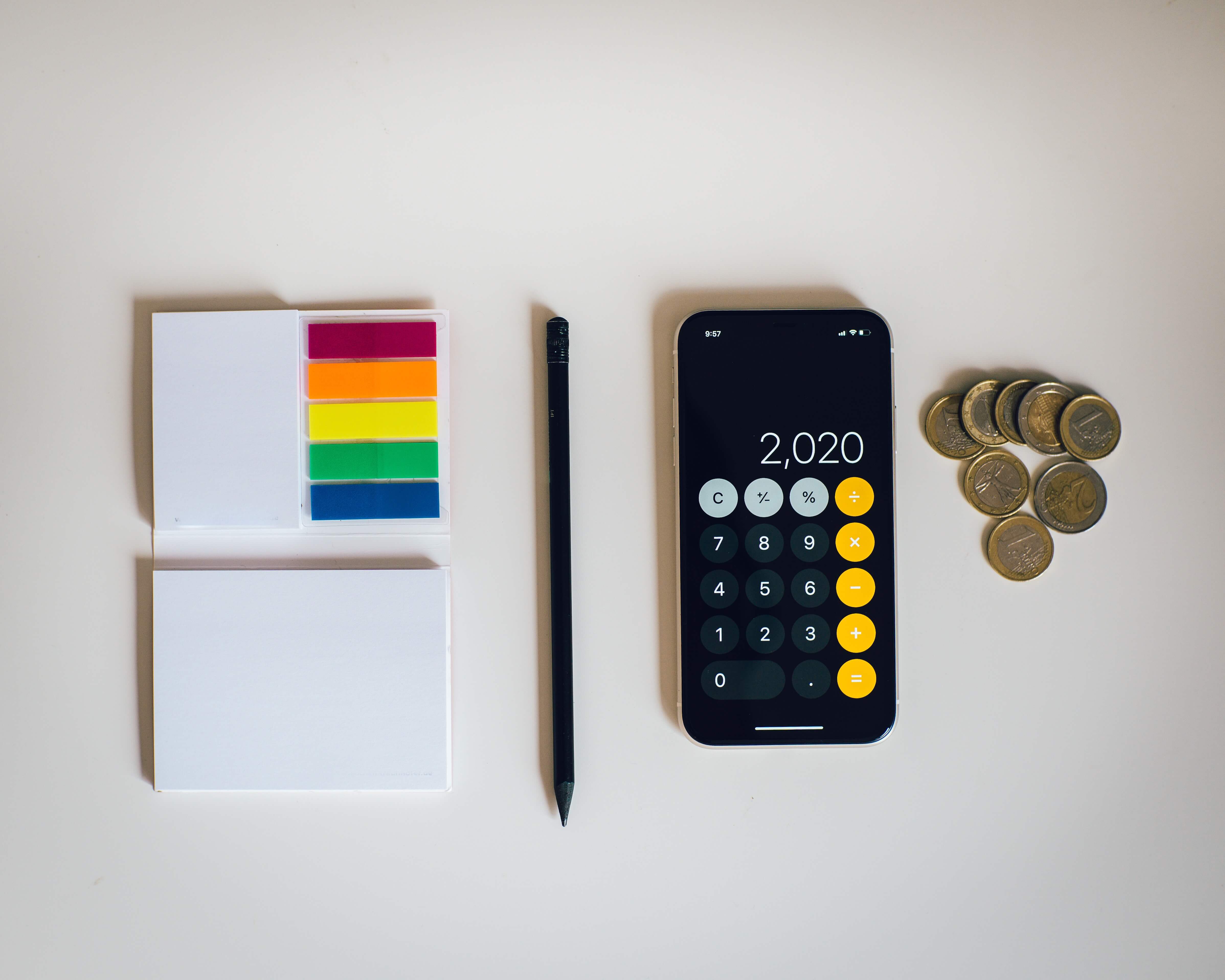 A calculator, pen, paper, and a pile of change