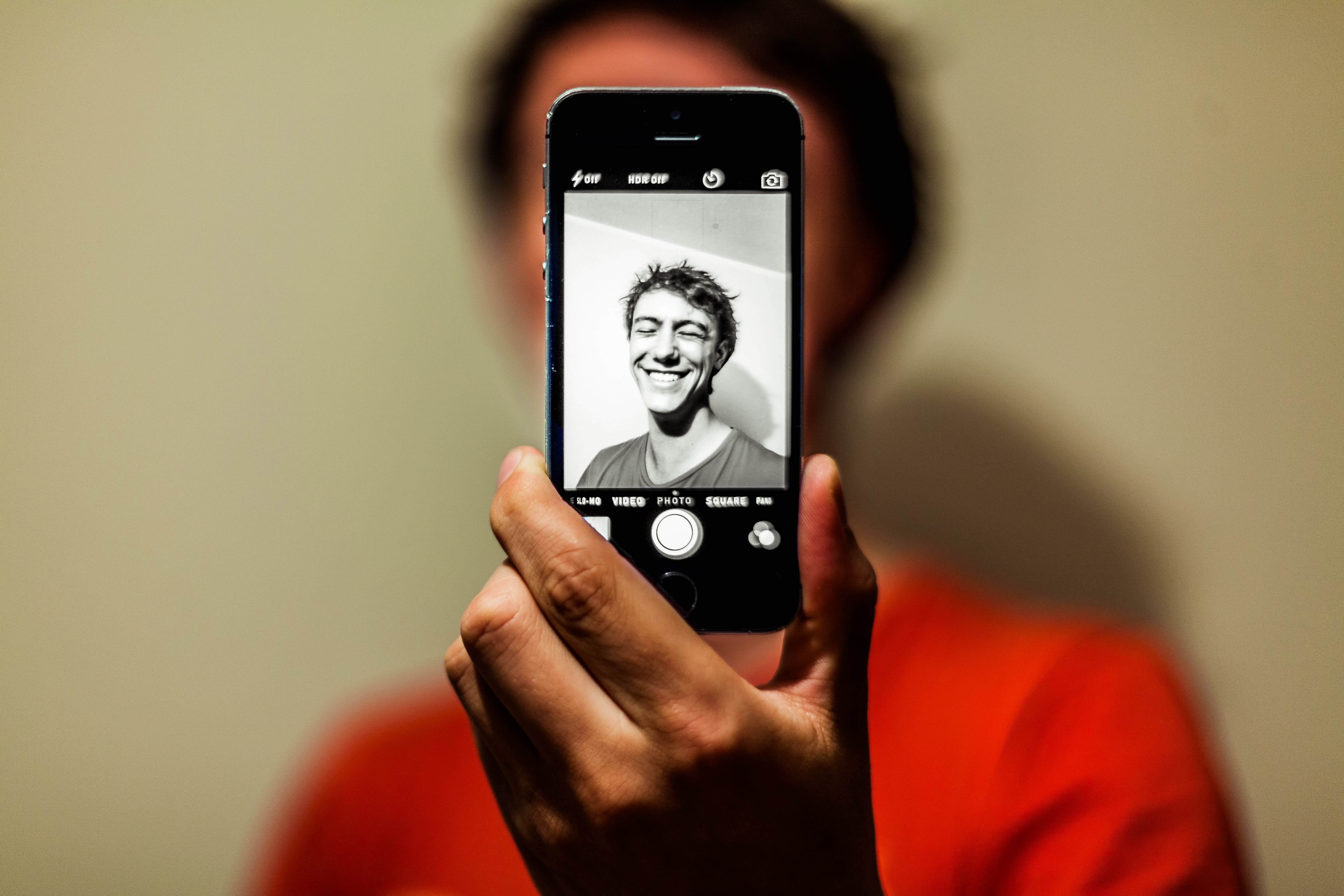 A young man taking a black and white selfie