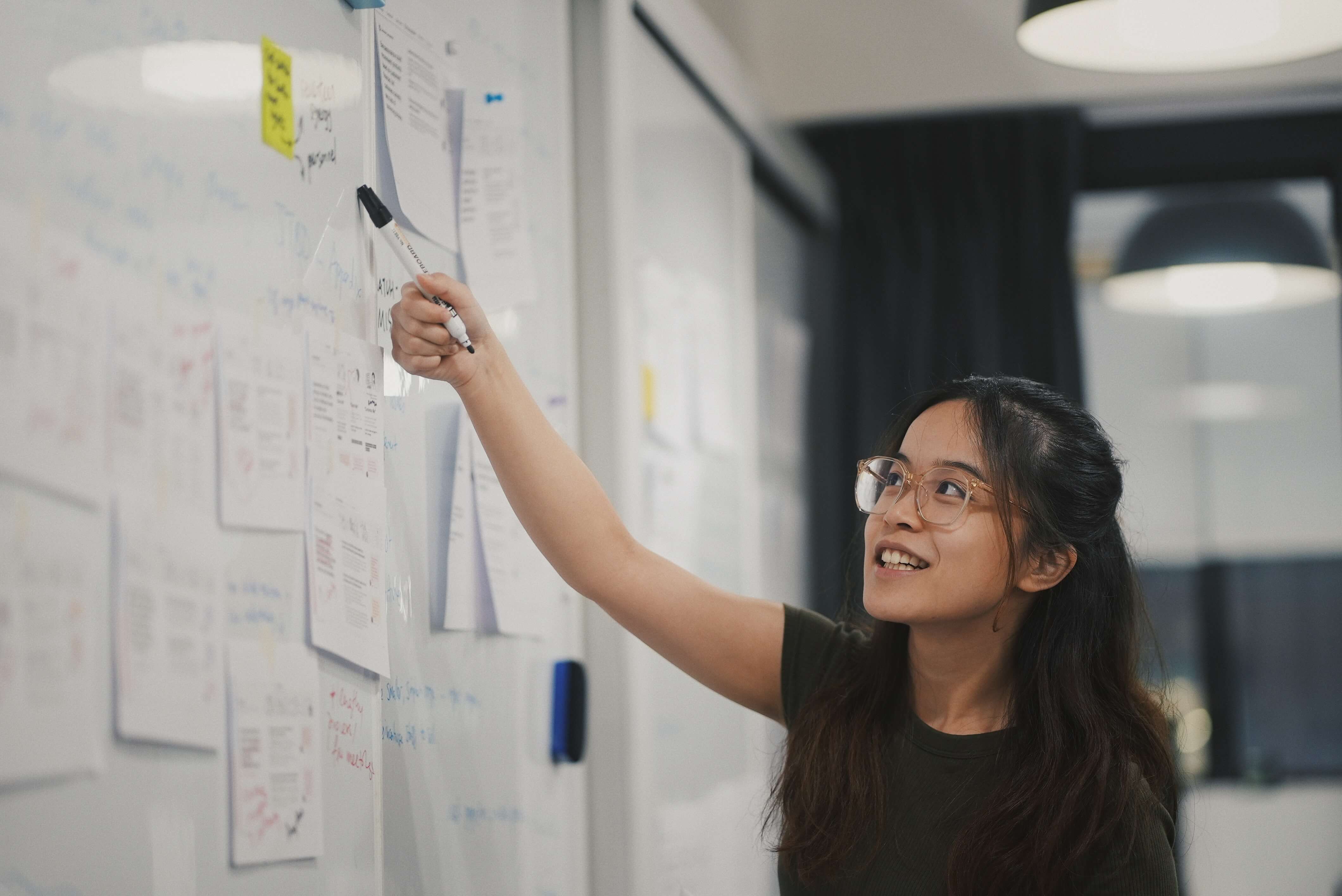 An East Asian girl points to something on a whiteboard