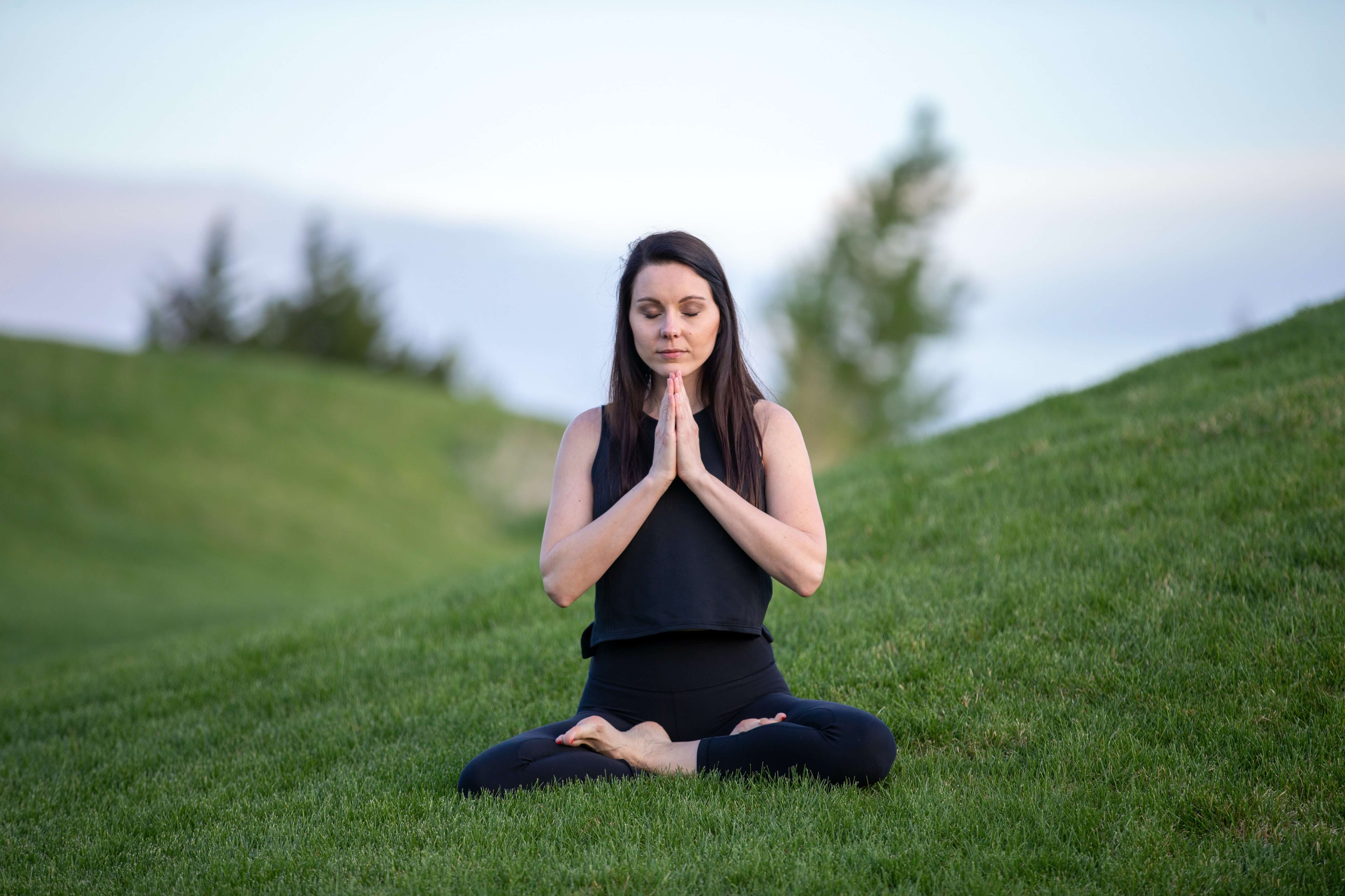 A woman sitting cross-legged with her hands clasped together