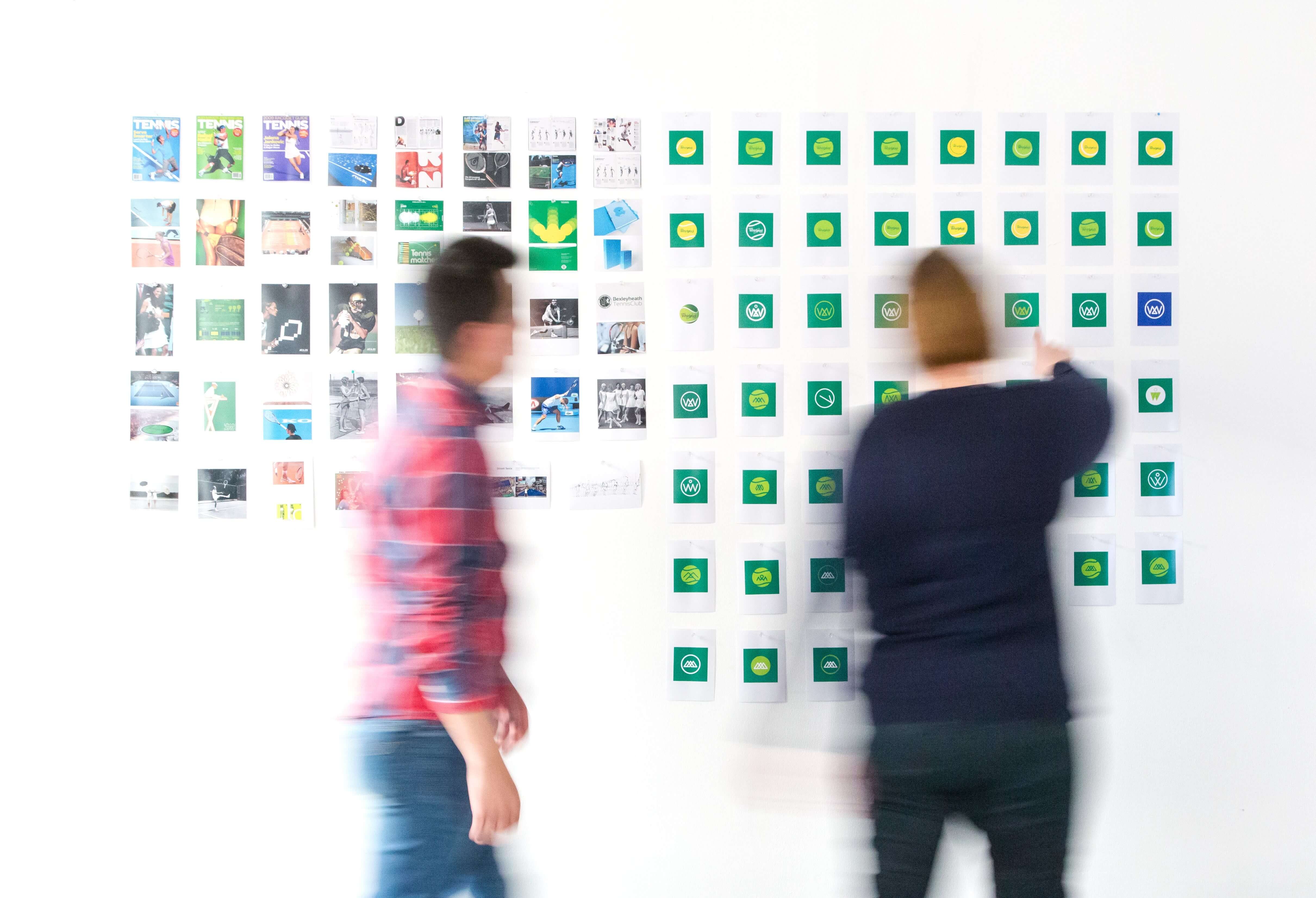 Two people pointing at index cards on a wall