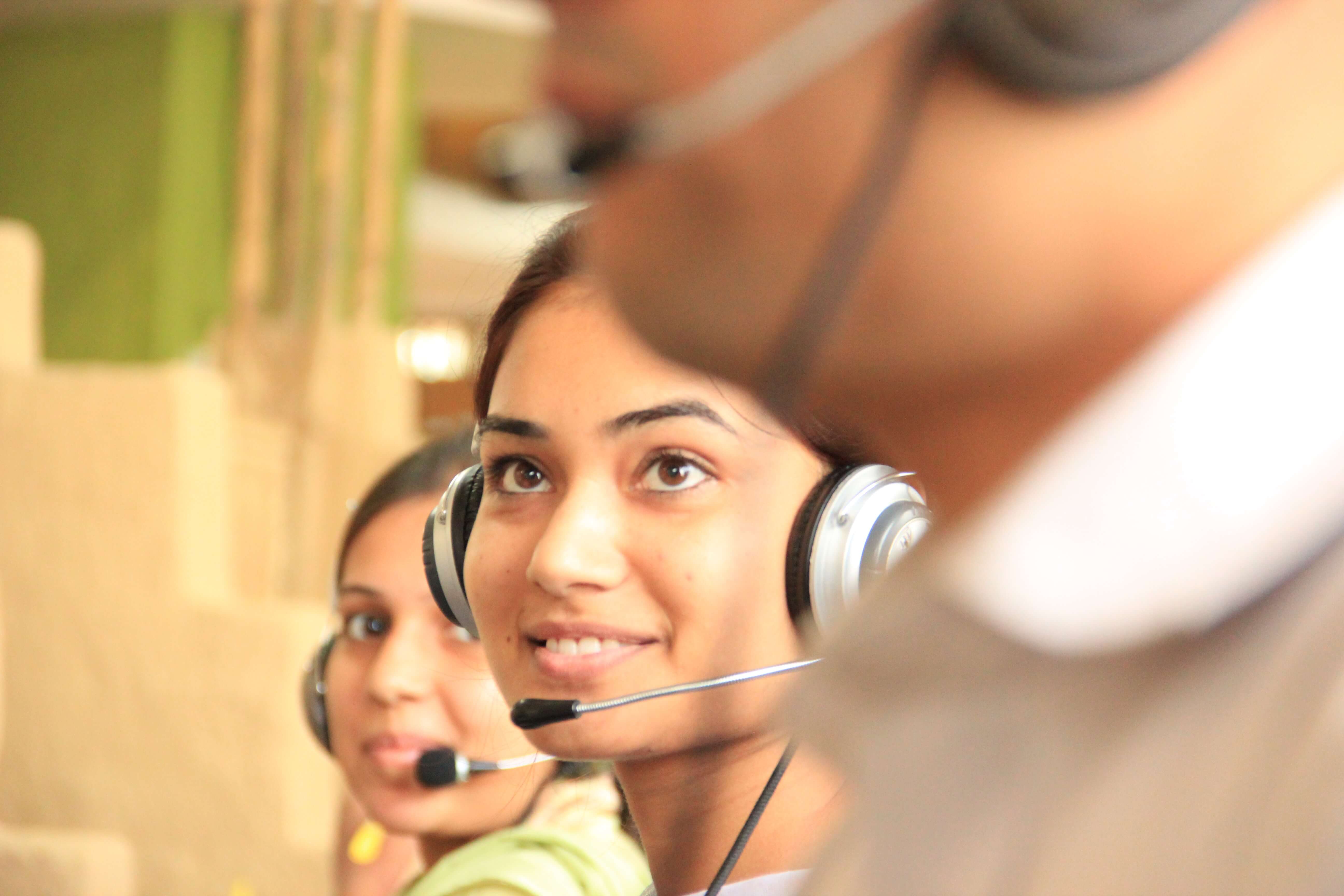 Three people wearing headsets with microphones working at a call center