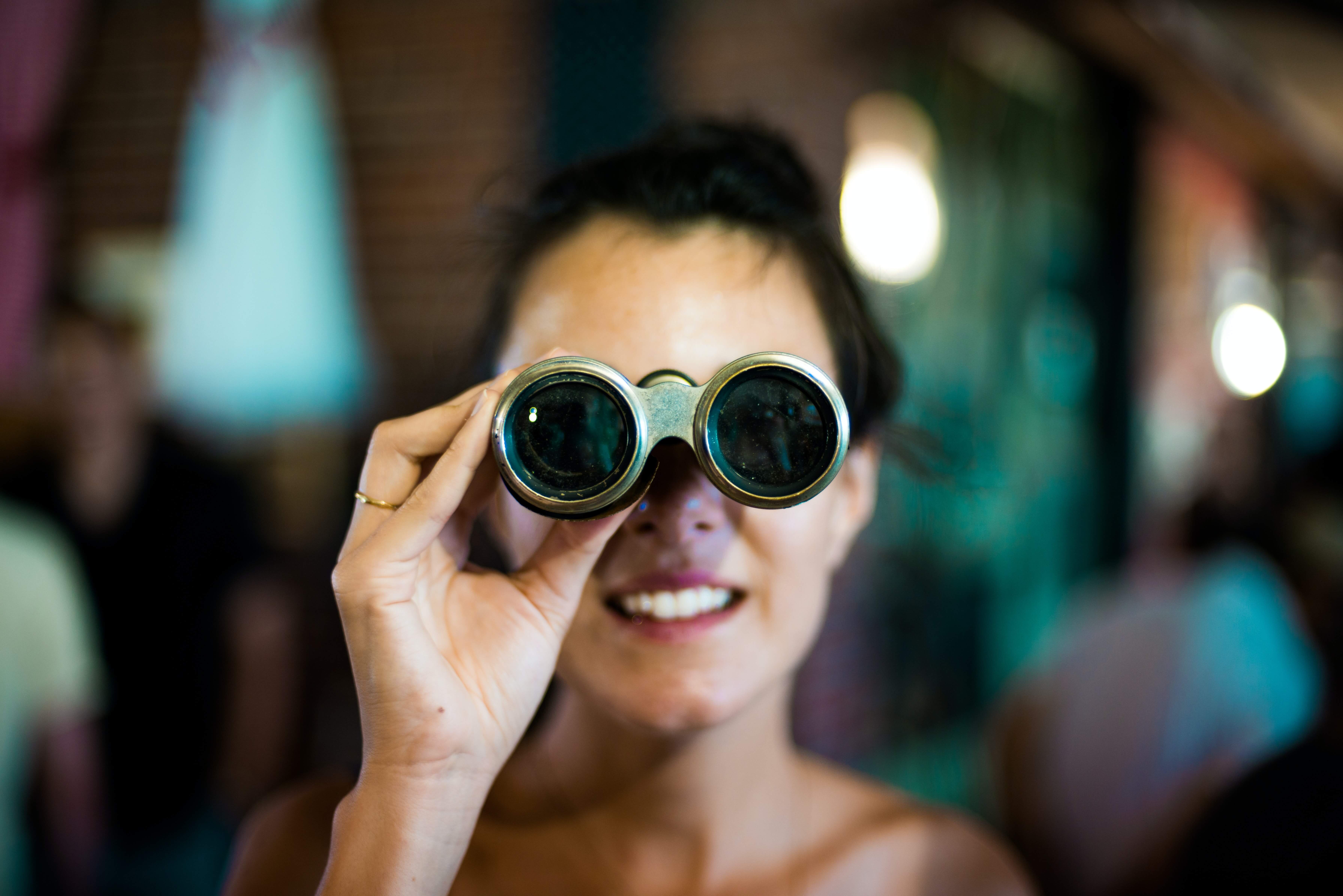 A dark-haired white woman using small binoculars