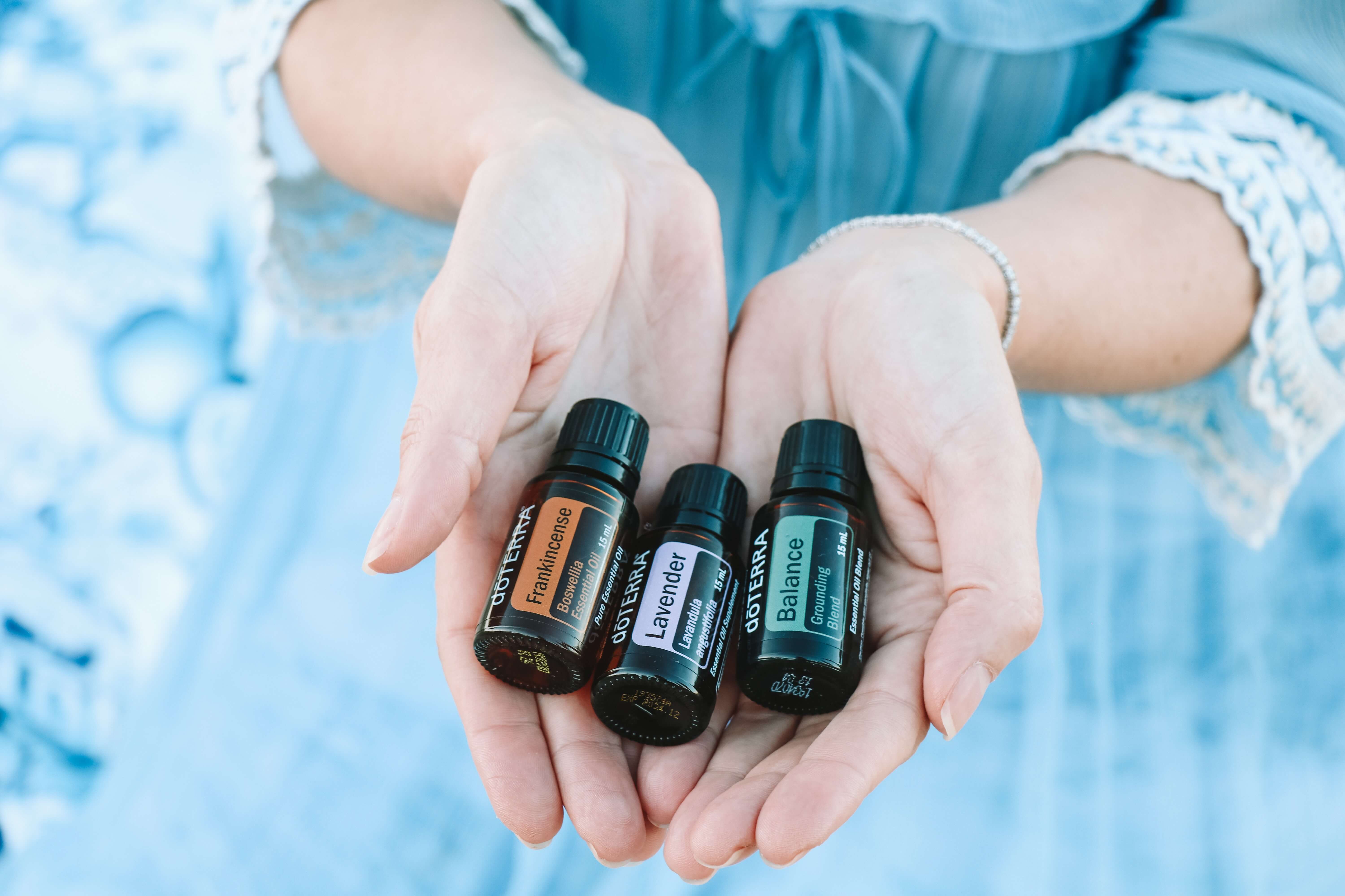 A woman holding out three bottles of essential oils
