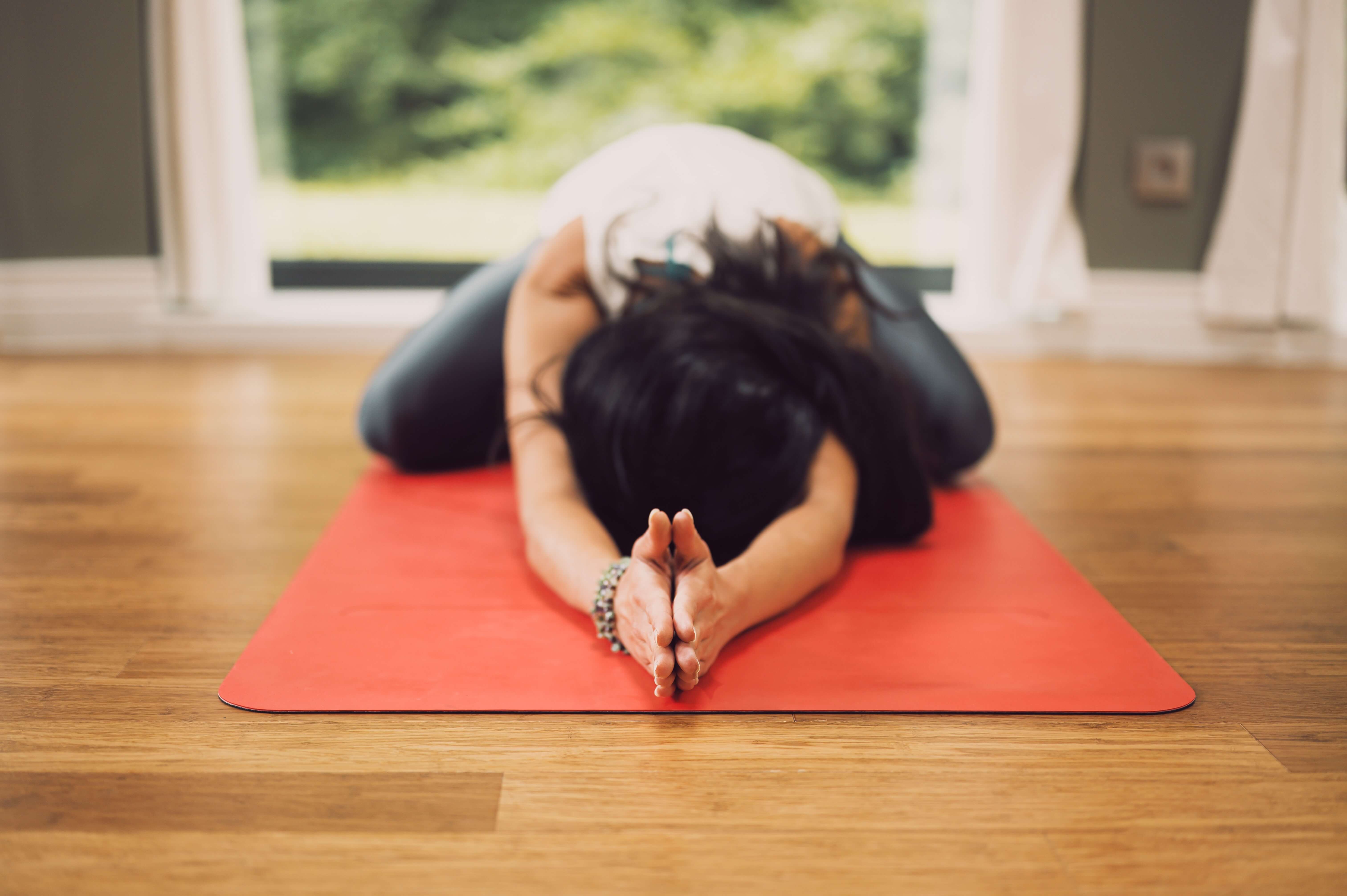 A white woman with dark hair does yoga on a mat