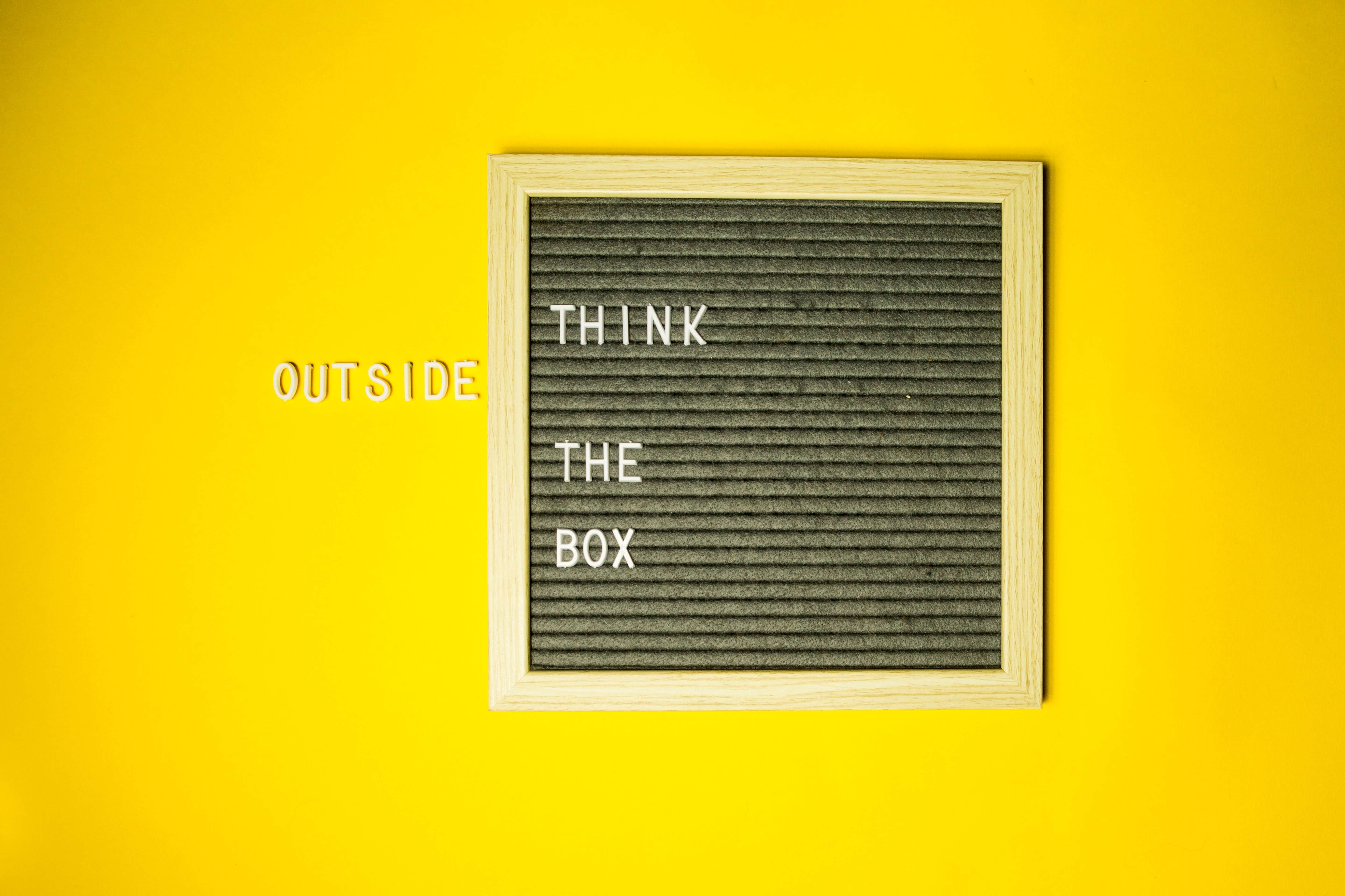 A letterboard that reads "think outside the box" with the word "outside" outside the board