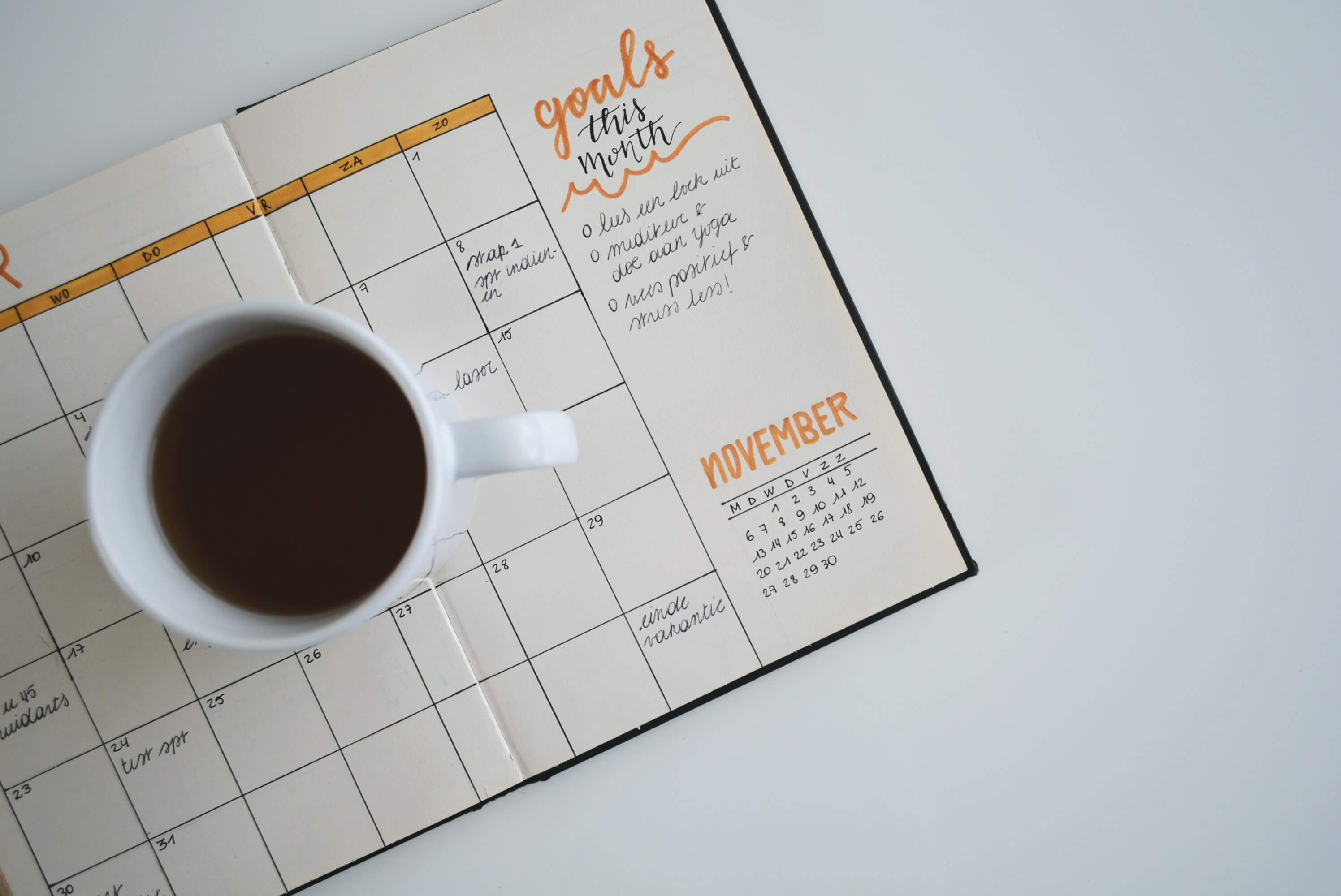 A cup of coffee sitting on an open planner