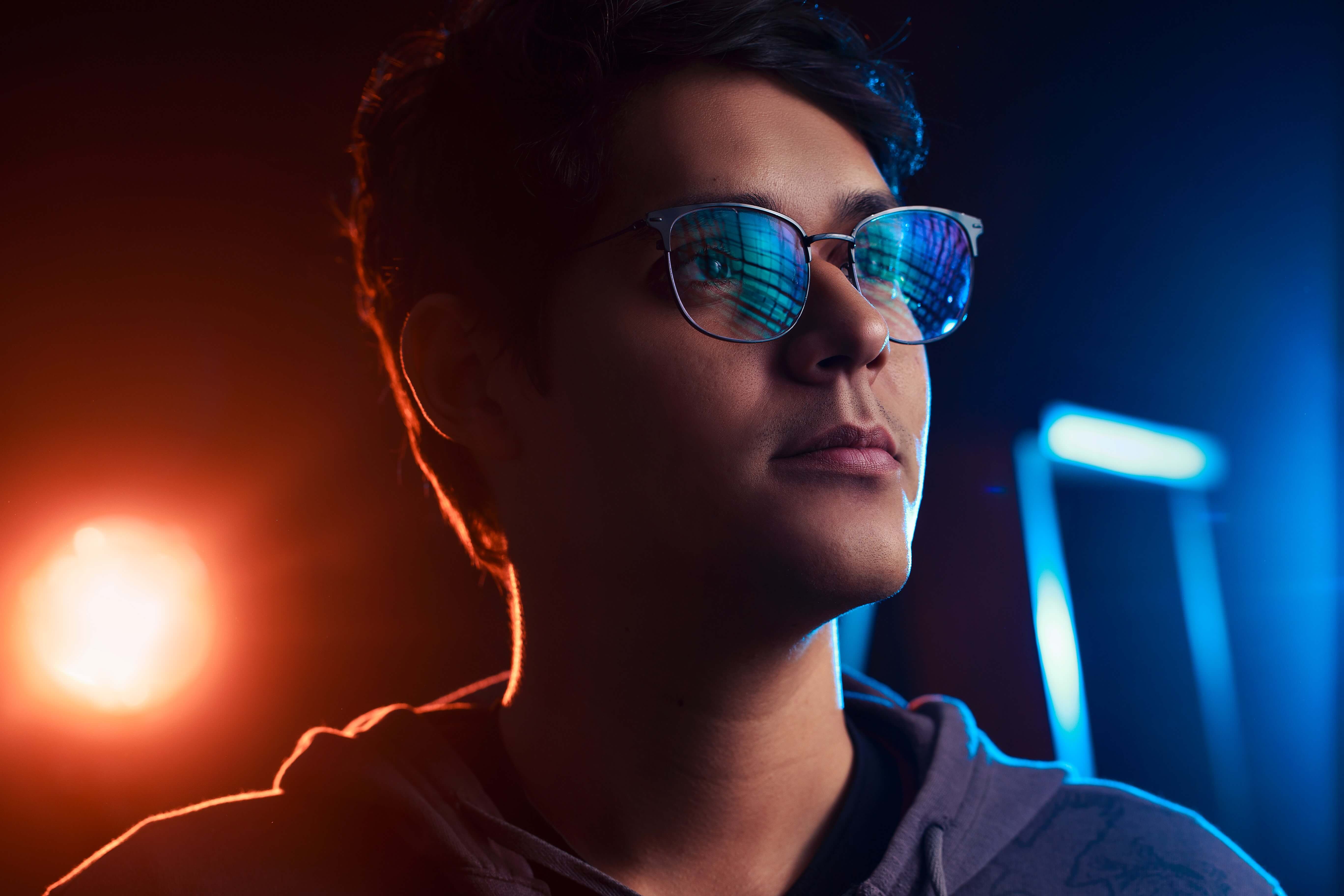 A young man with dark hair models blue light blocking glasses.