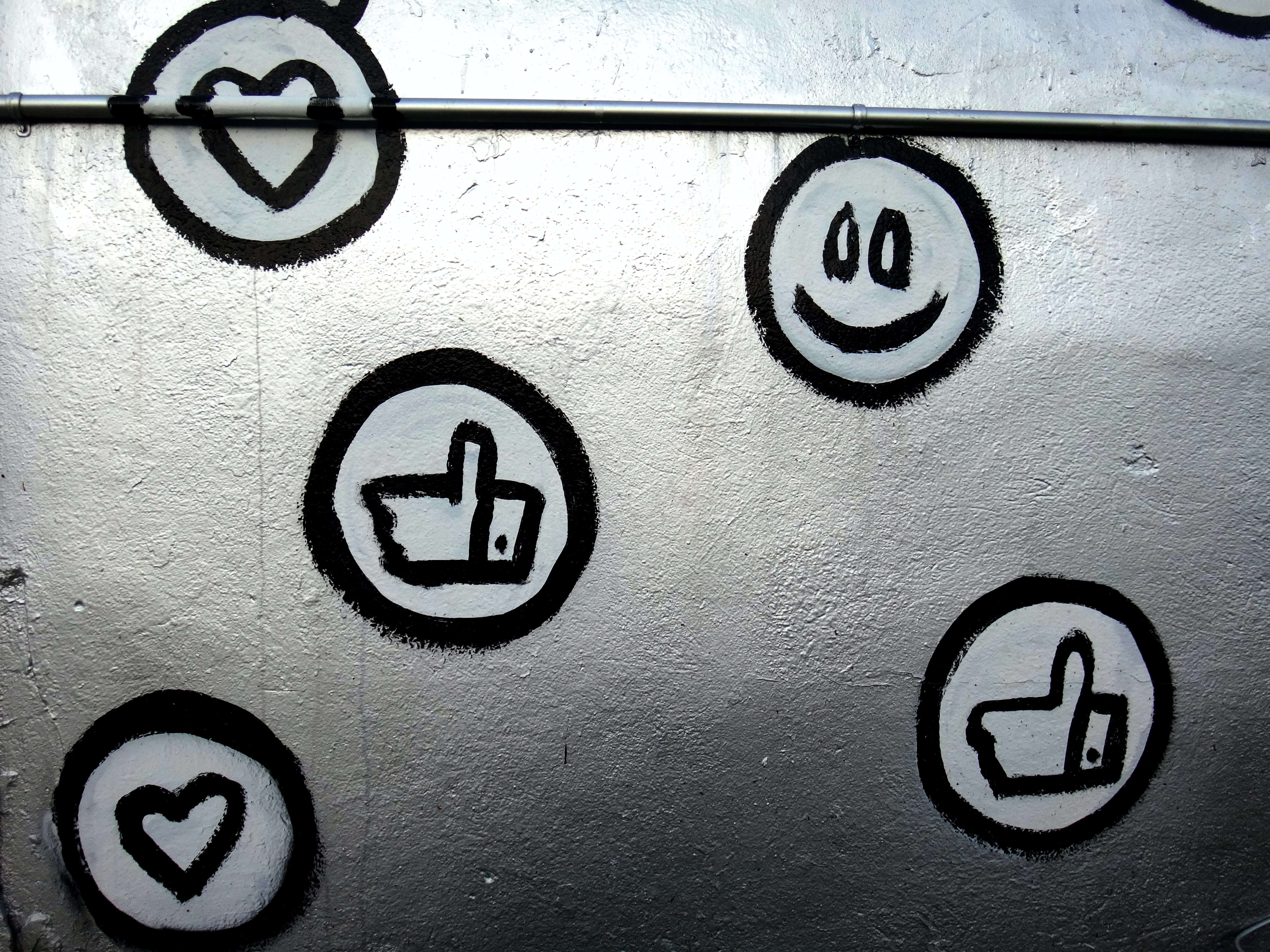 Thumbs up, heart, and smiley face icons spray painted on a wall