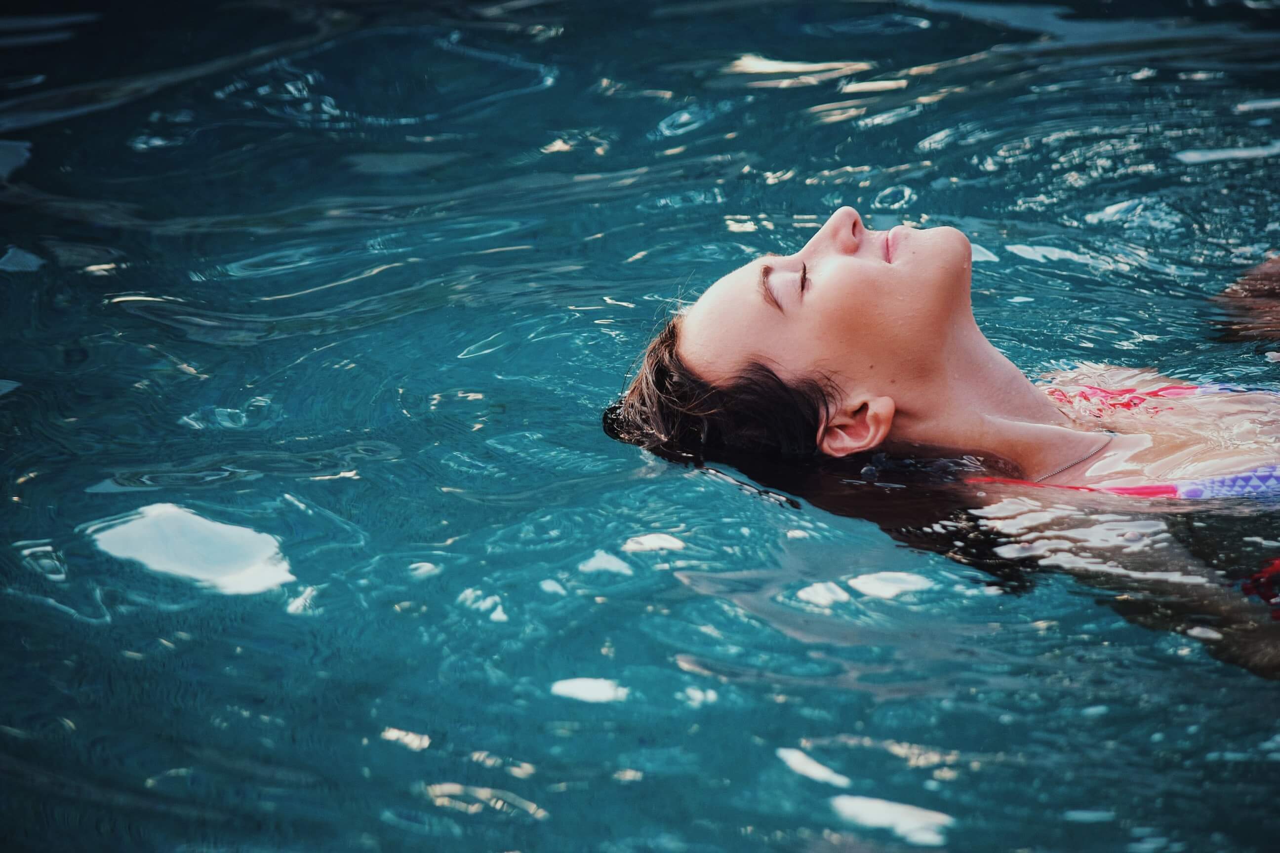 A person lying down face-up in a pool