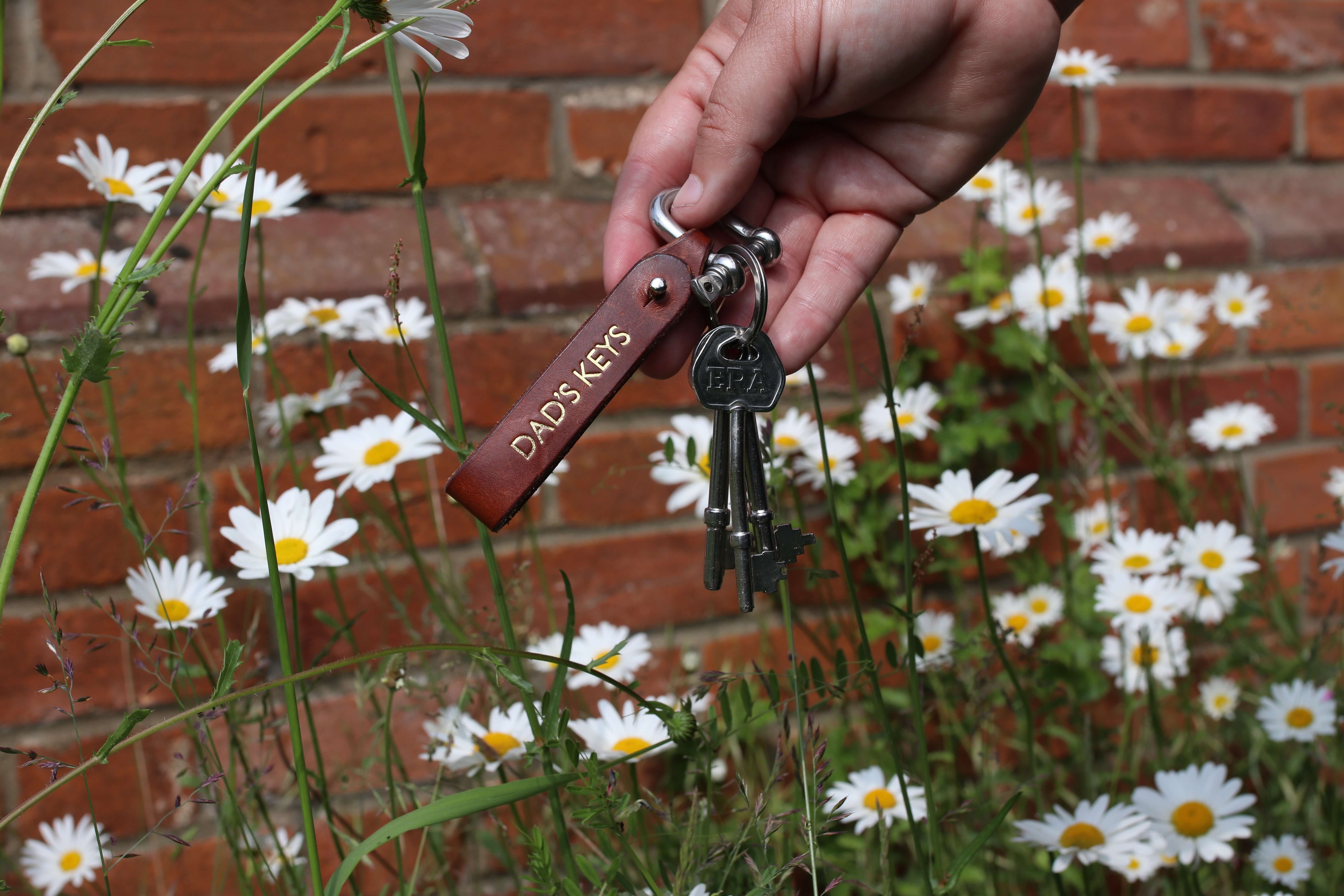 A leather keychain that reads "DAD'S KEYS" on a ring of keys