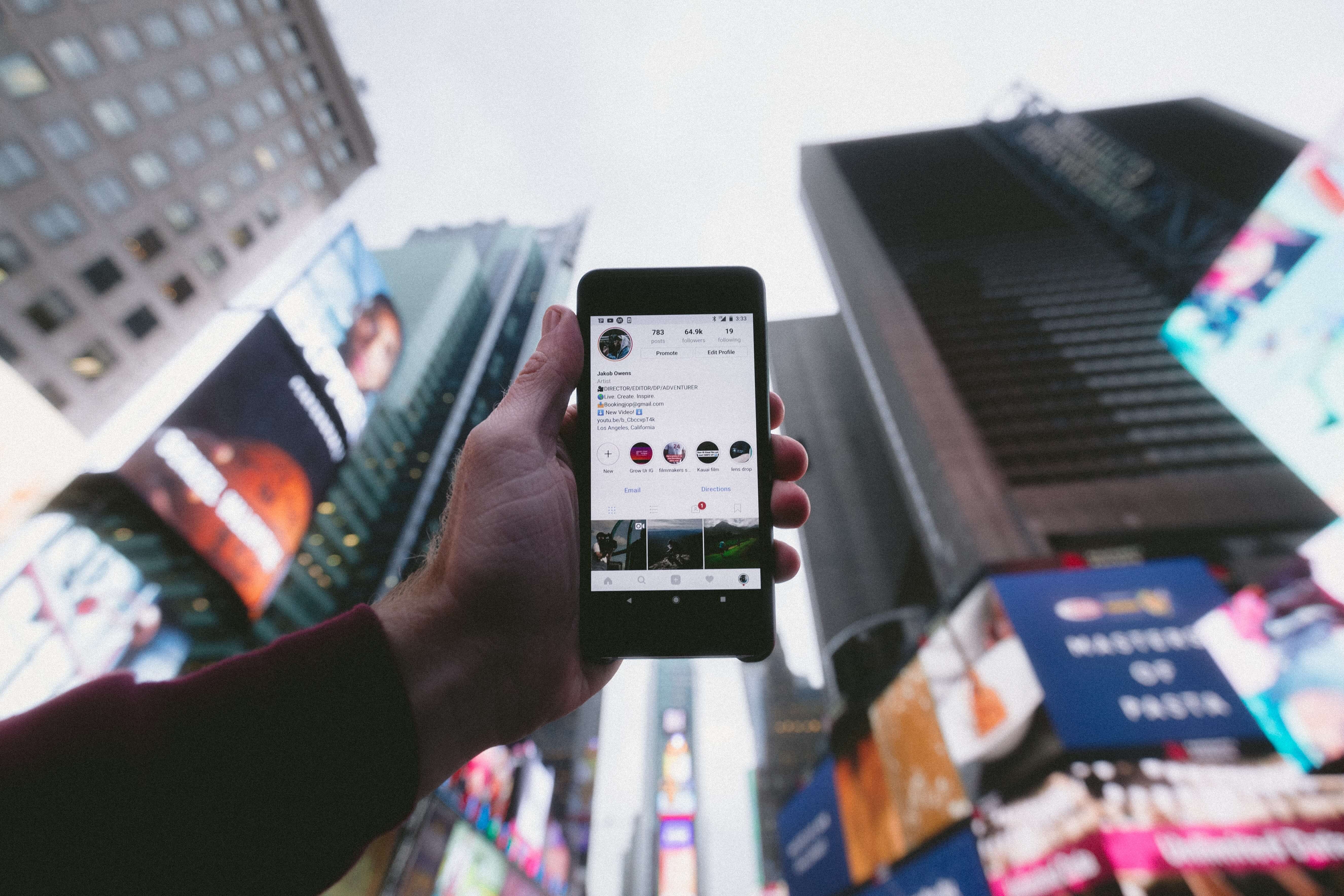 A hand using a smartphone to take a picture of Times Square