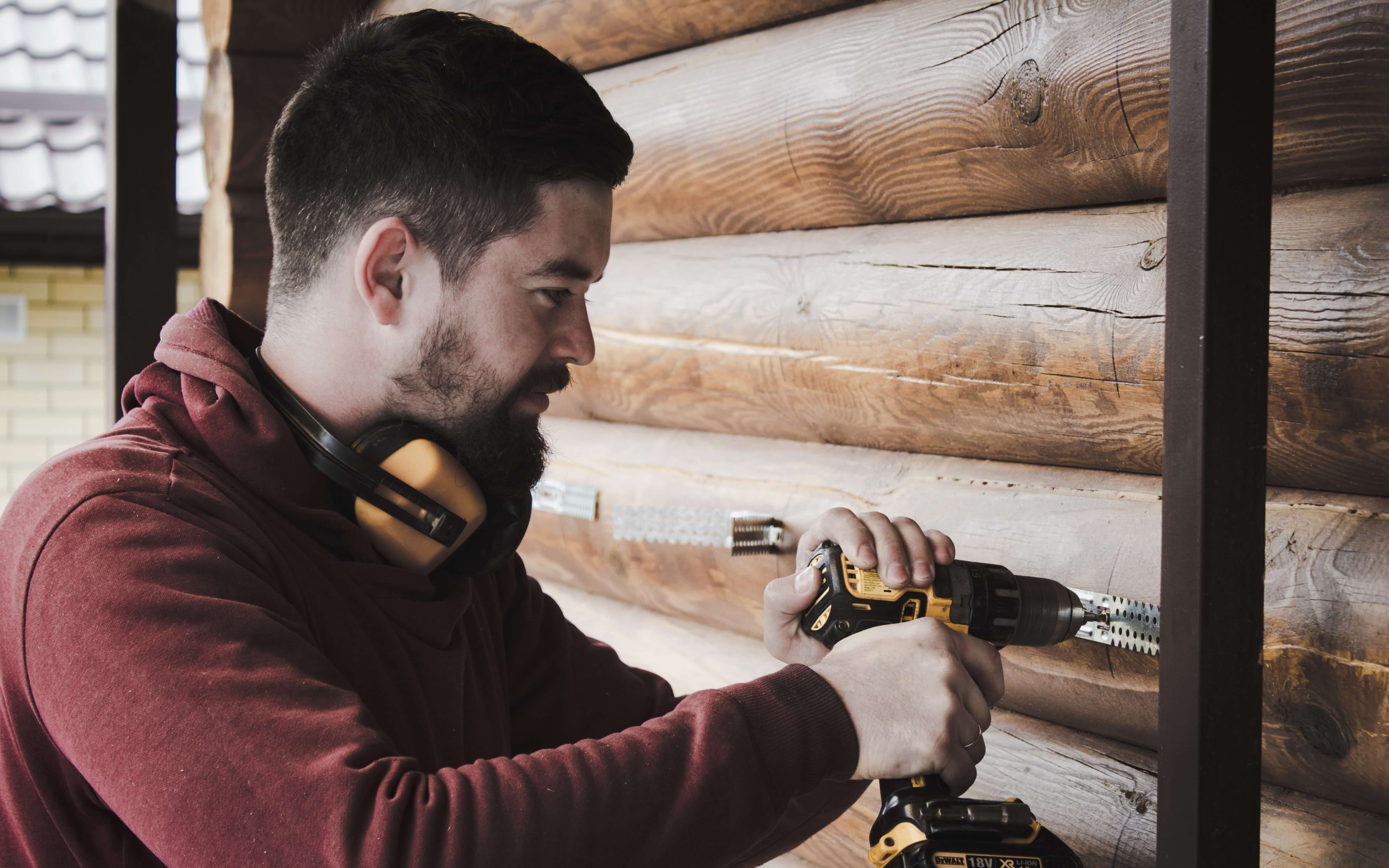 A man with a beard uses an electric drill.