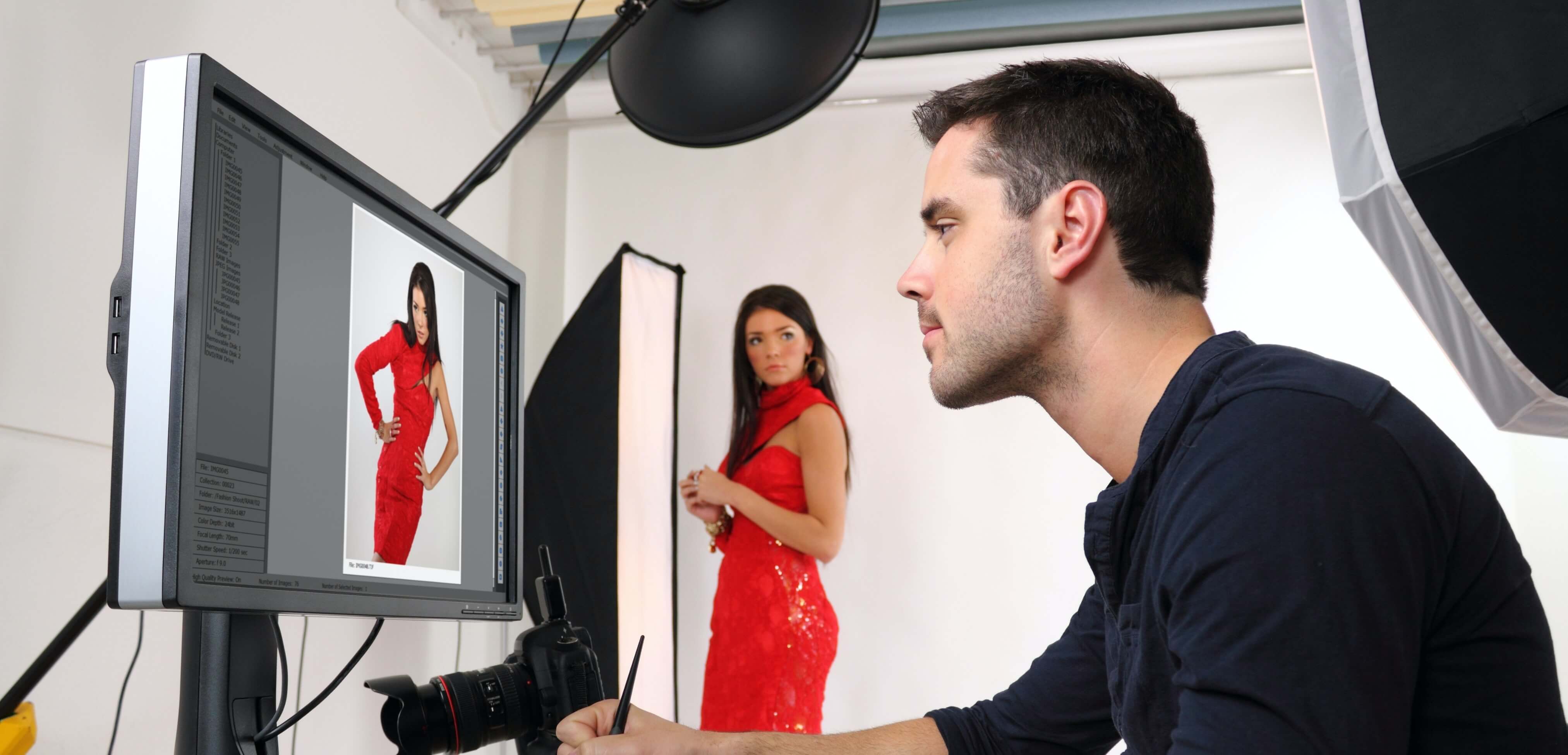 A man retouching a photo of a woman modeling a red dress