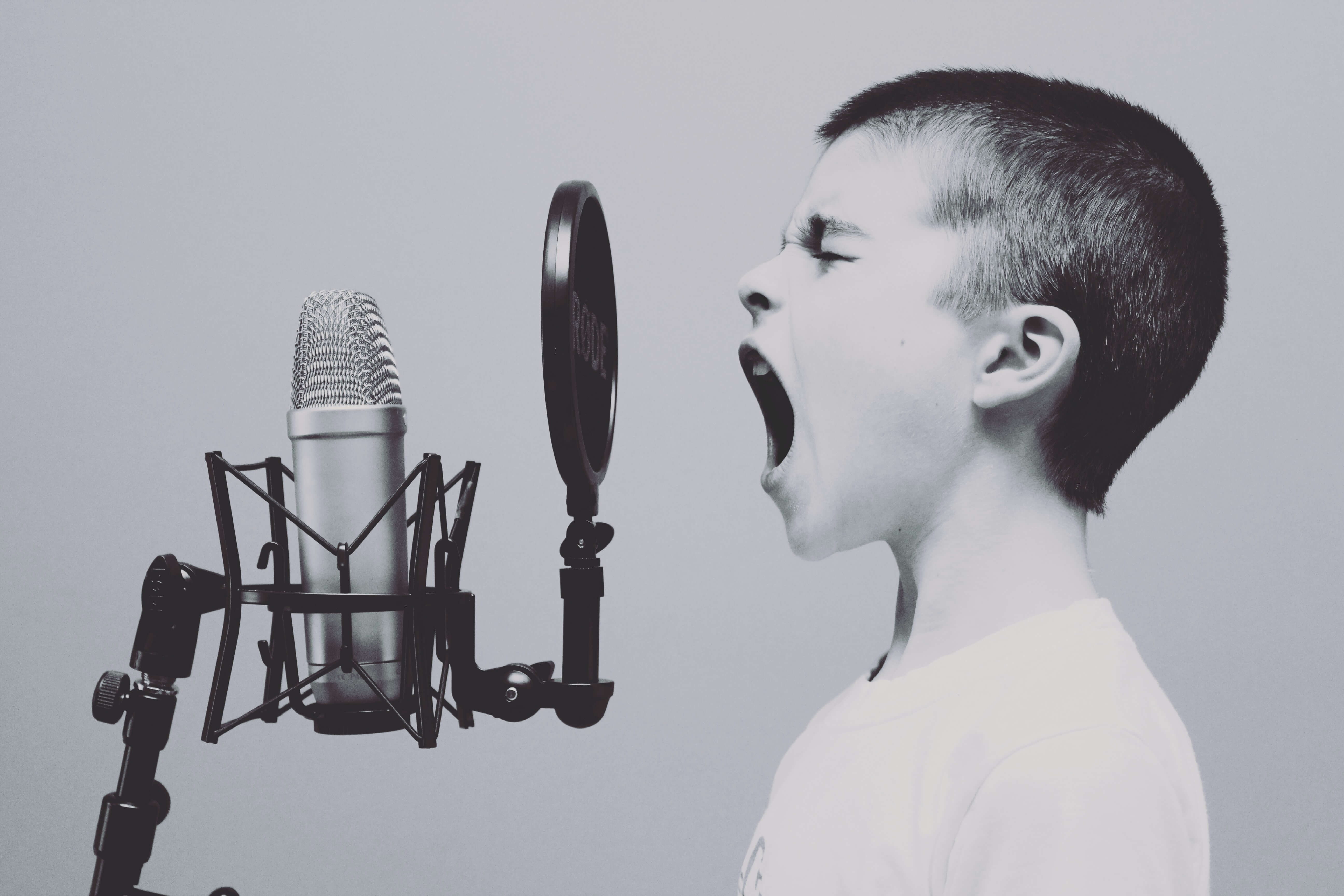 A black and white photo of a child screaming into a microphone