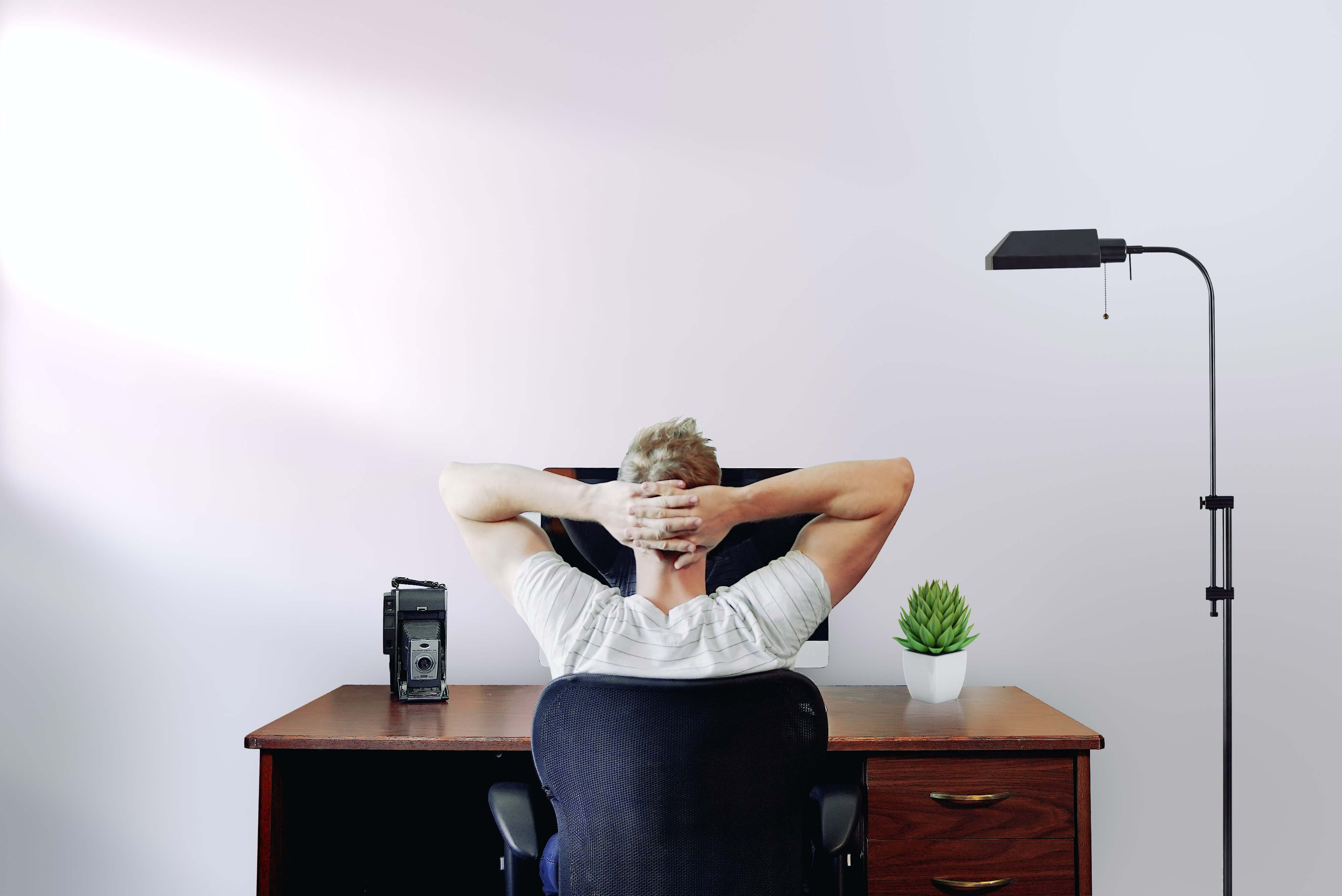 A back view of a blond young man working from home
