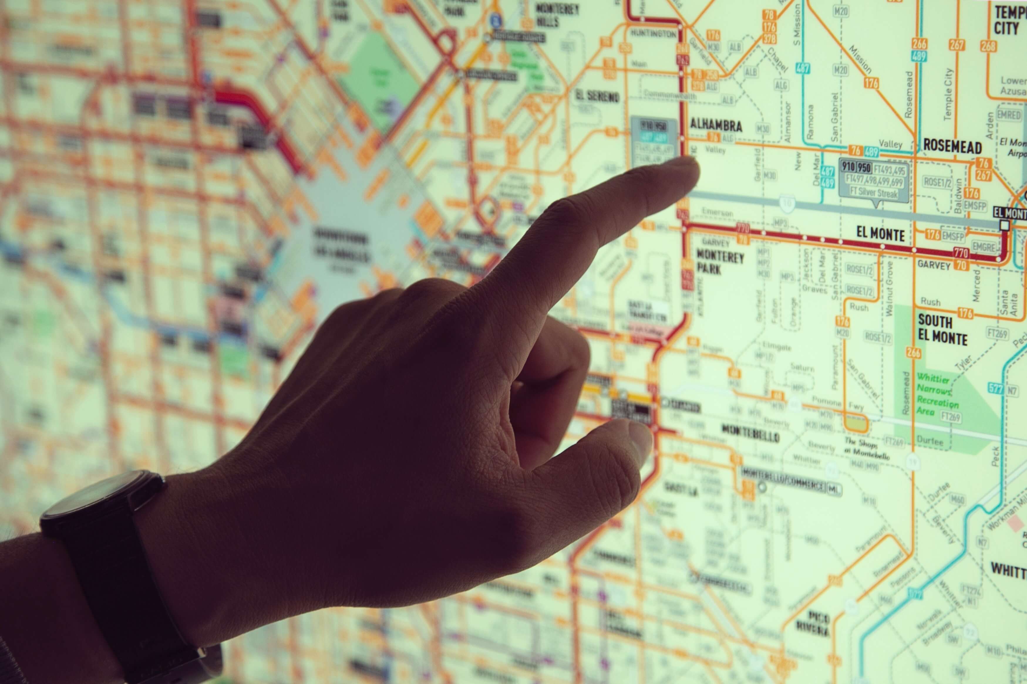 A hand pointing at a map on a screen