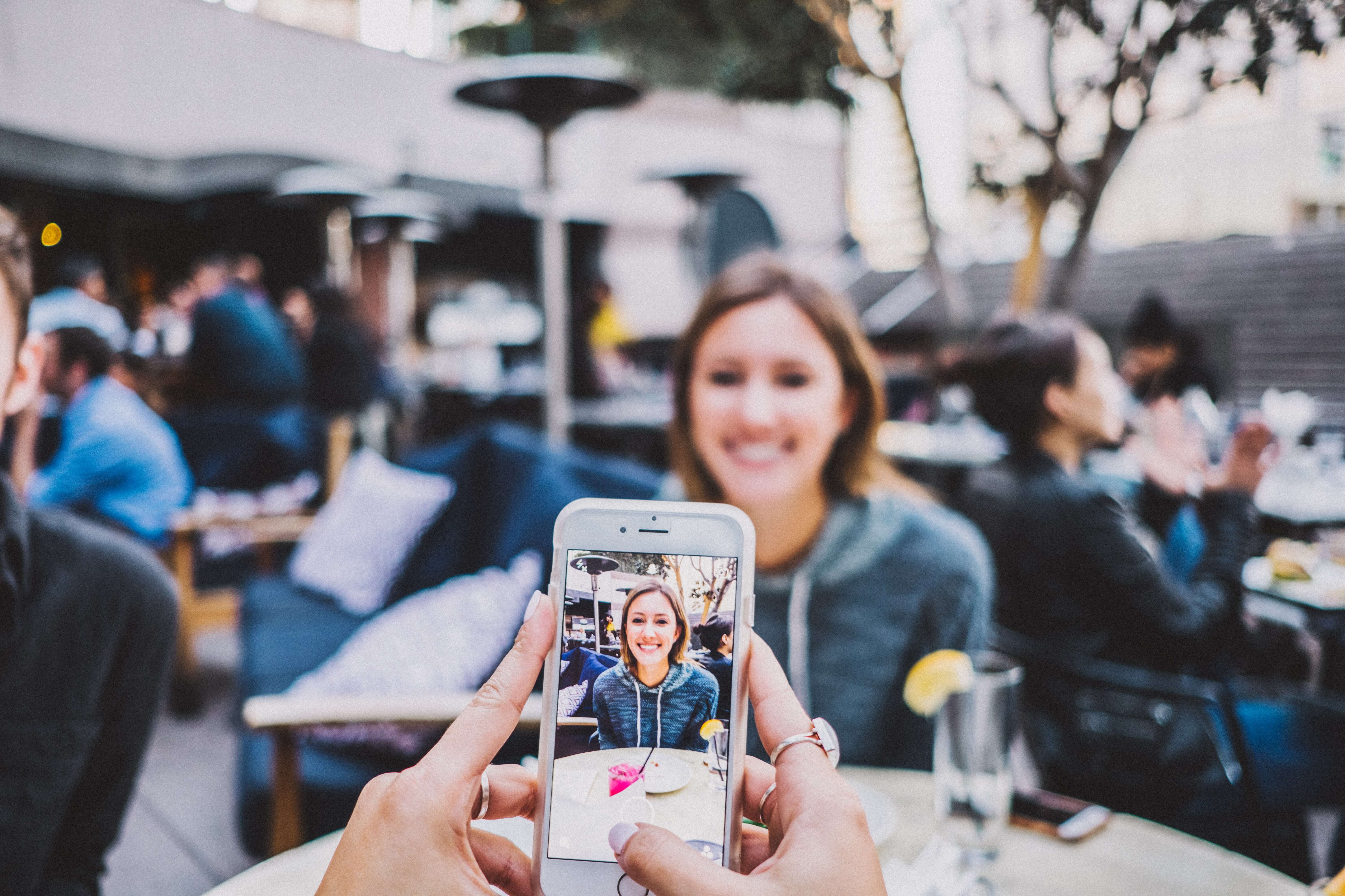 Someone taking a photo of a young white woman on a smartphone