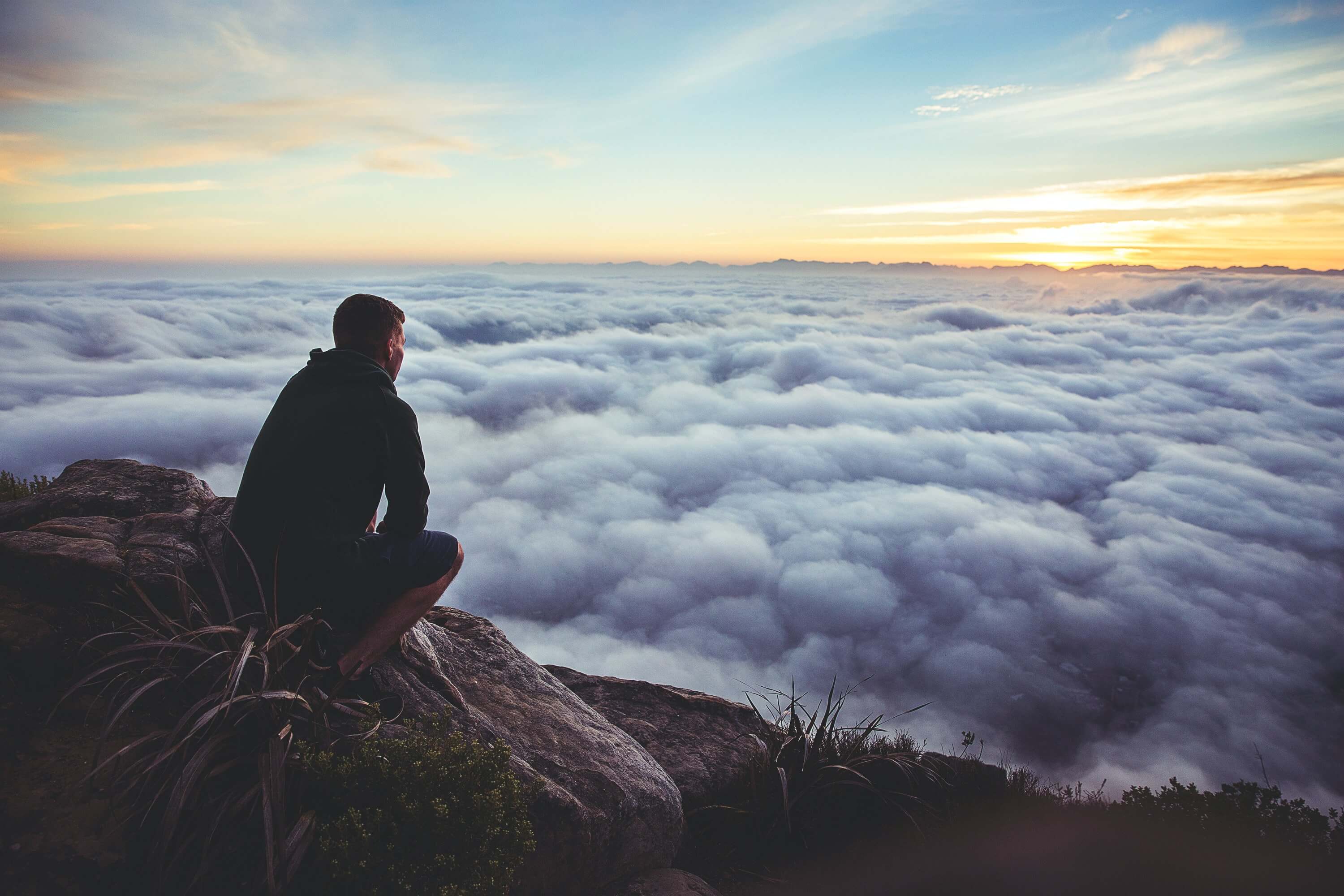 A hiker overlooking a sea of clouds at sunset