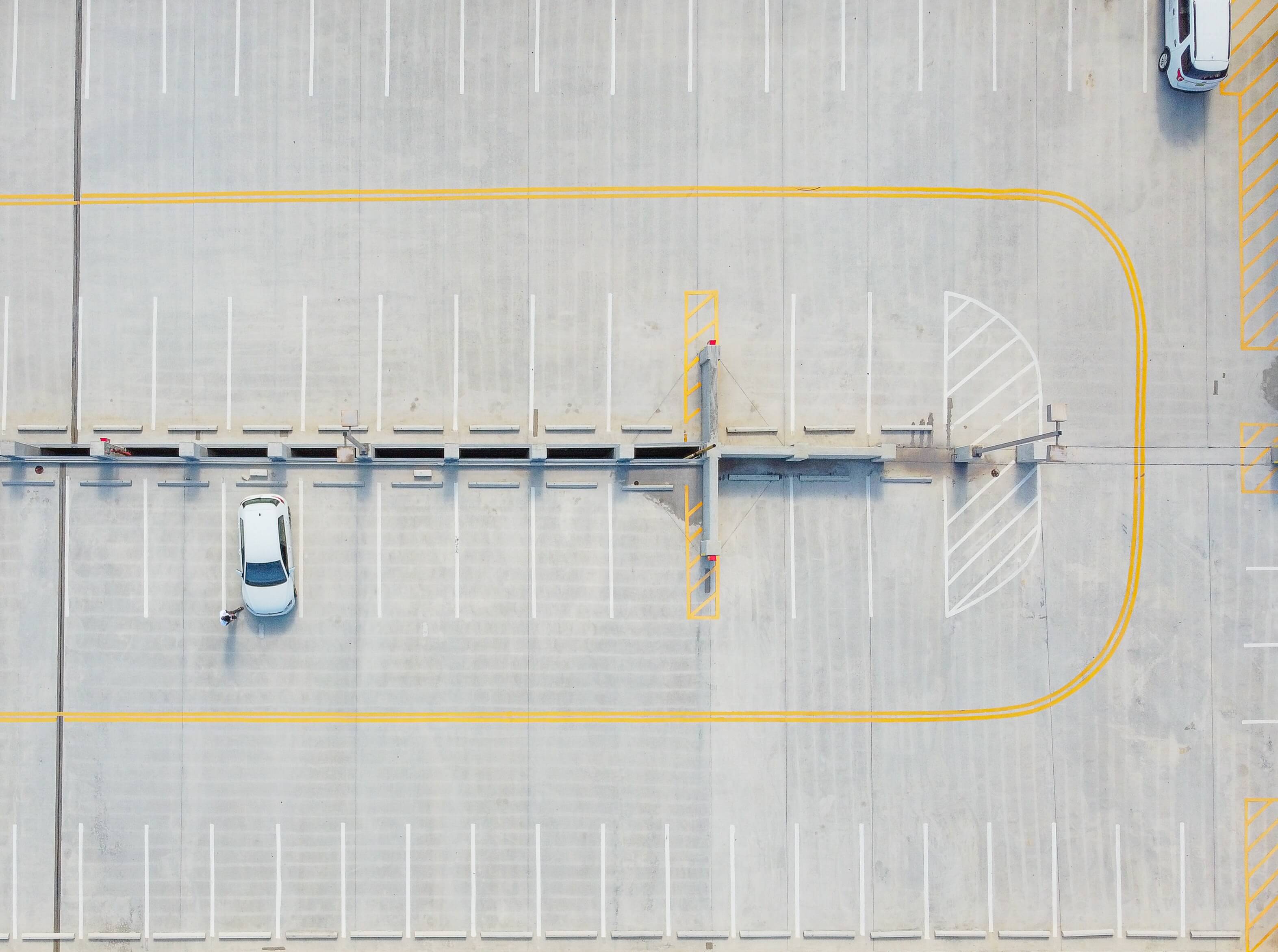 An aerial shot of a parking lot with one car parked in it