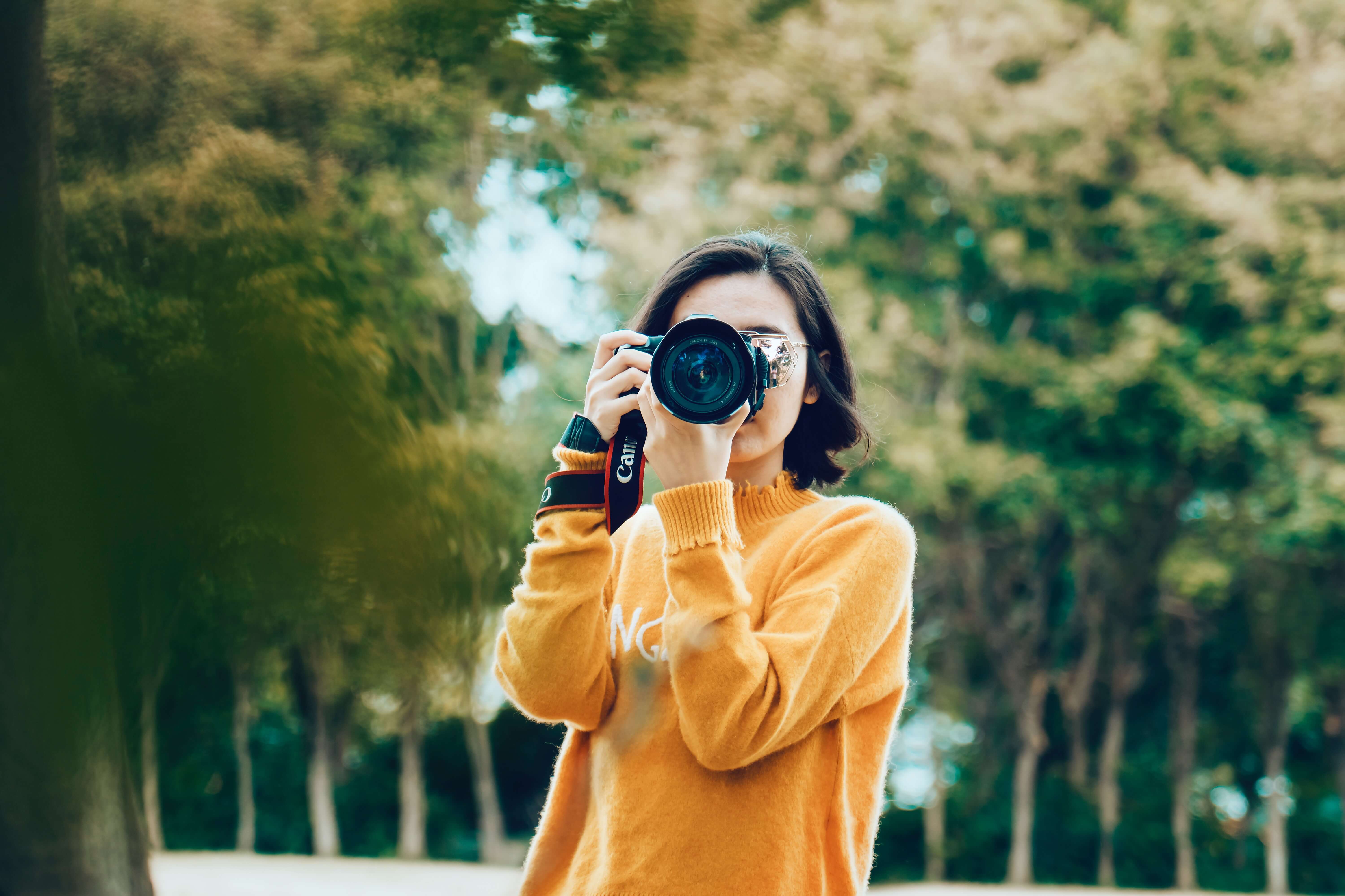 An east Asian woman taking a photo with a camera