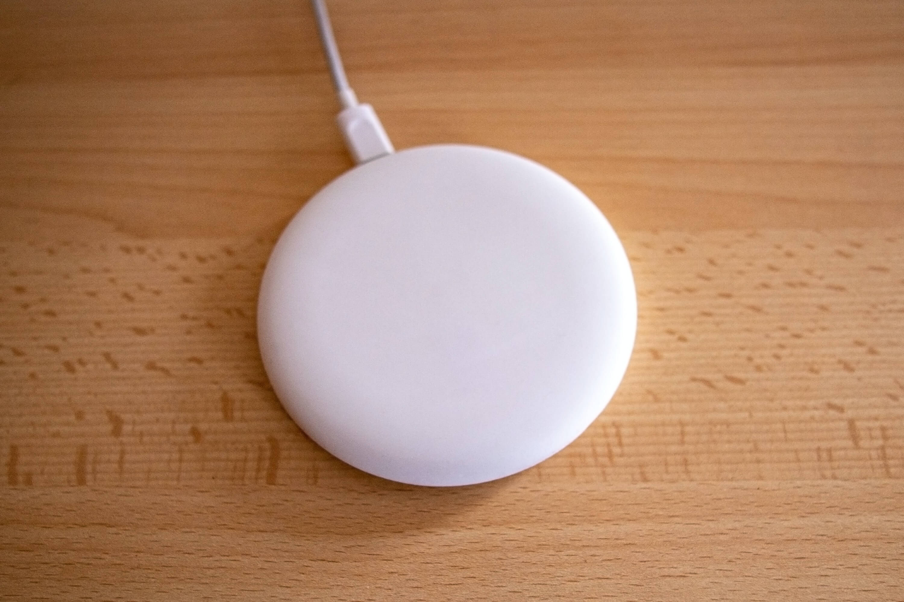 A white wireless charger on a wood counter