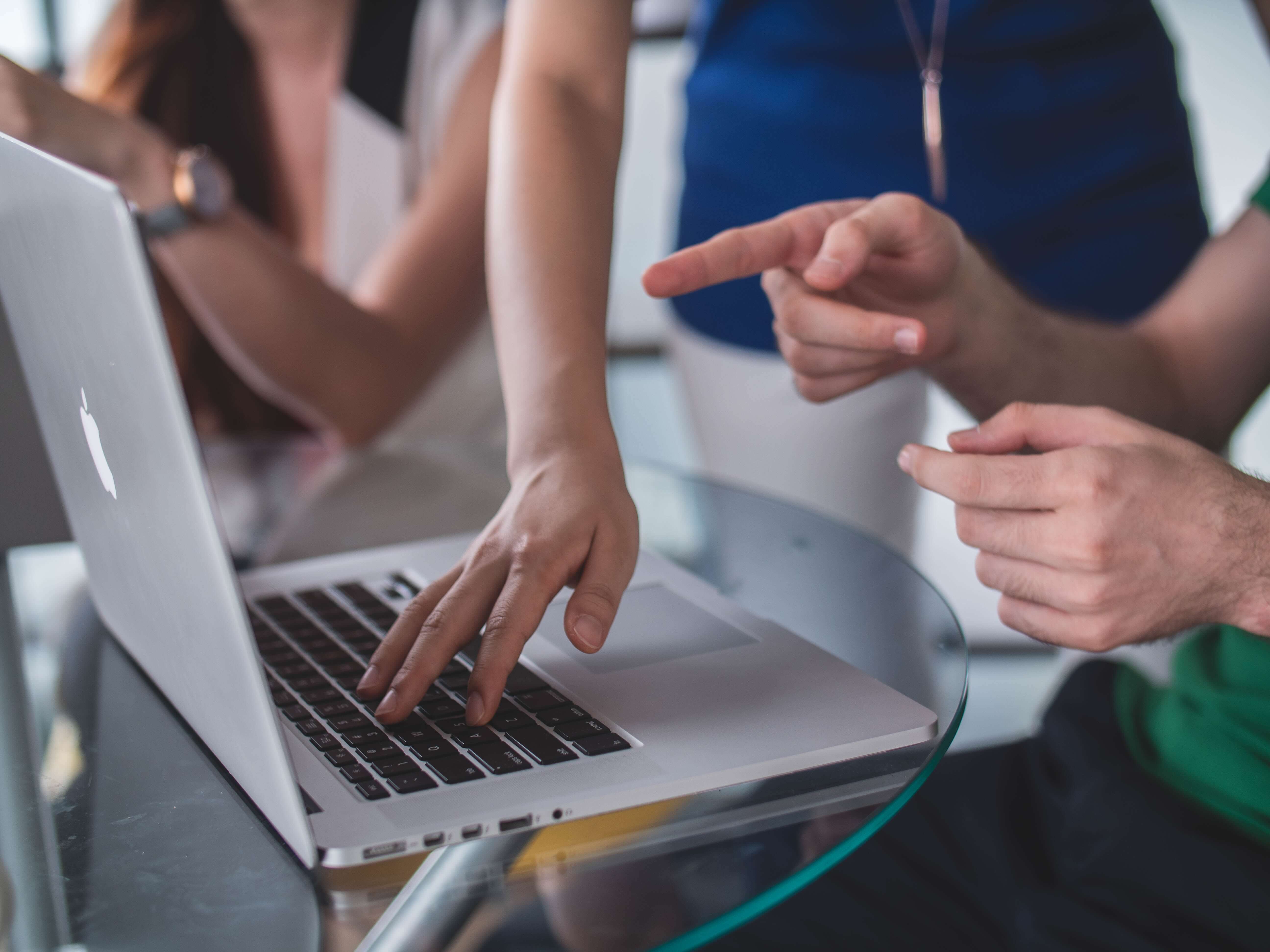 Multiple people pointing at a laptop screen