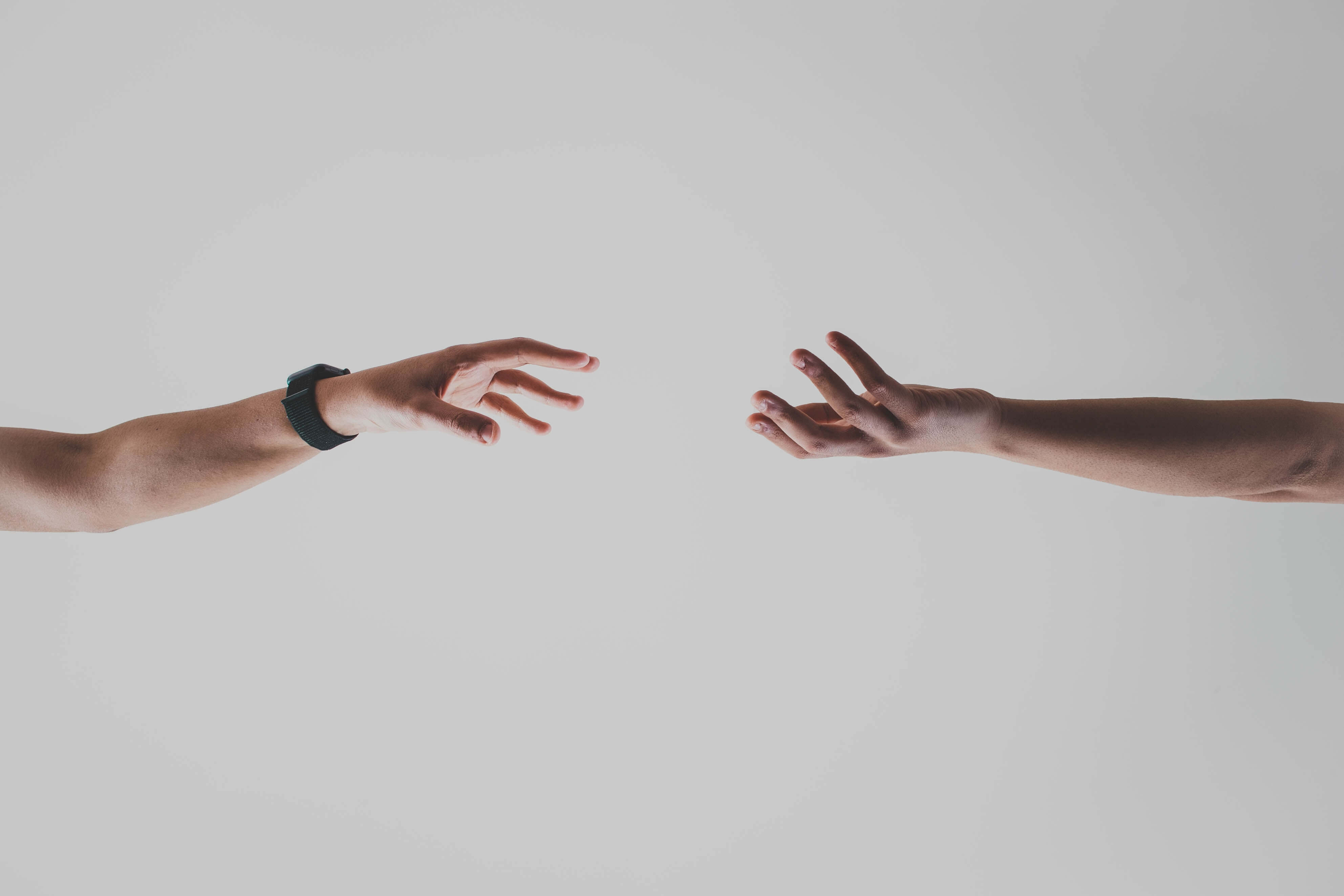 Two hands reaching towards each other against a white background