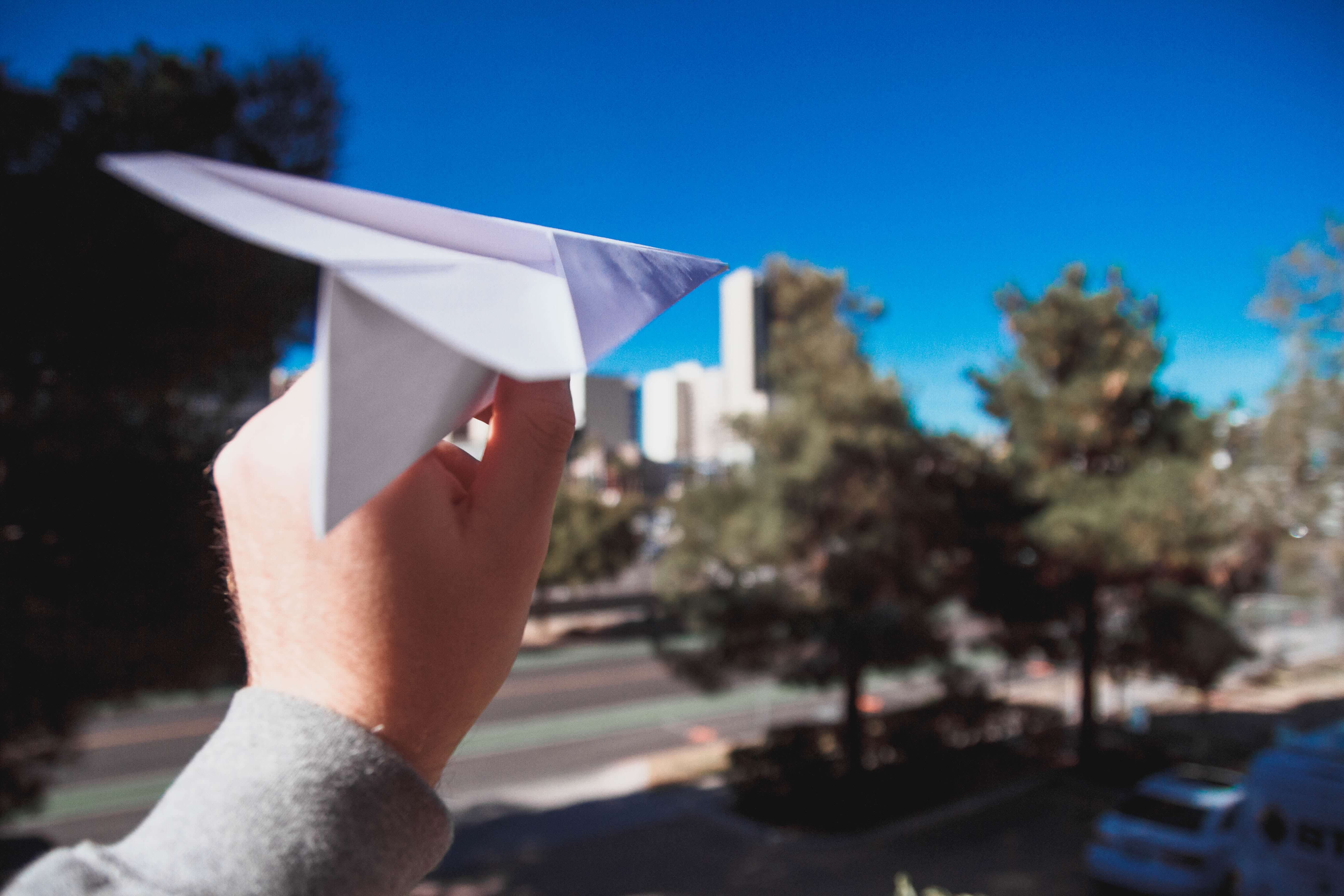 A person launching a paper airplane