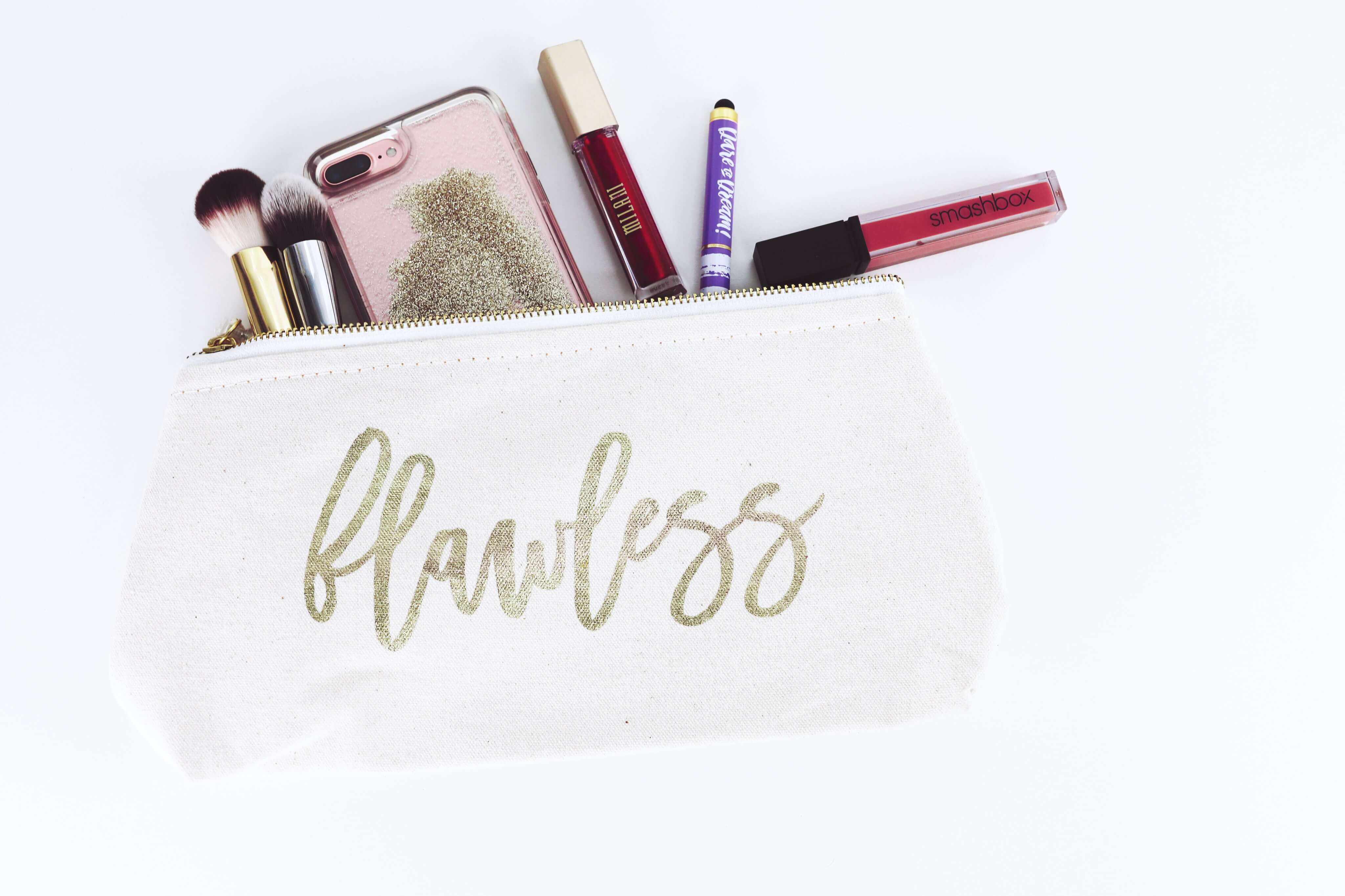 A makeup bag with the word "flawless" in gold cursive letteringprinted on it