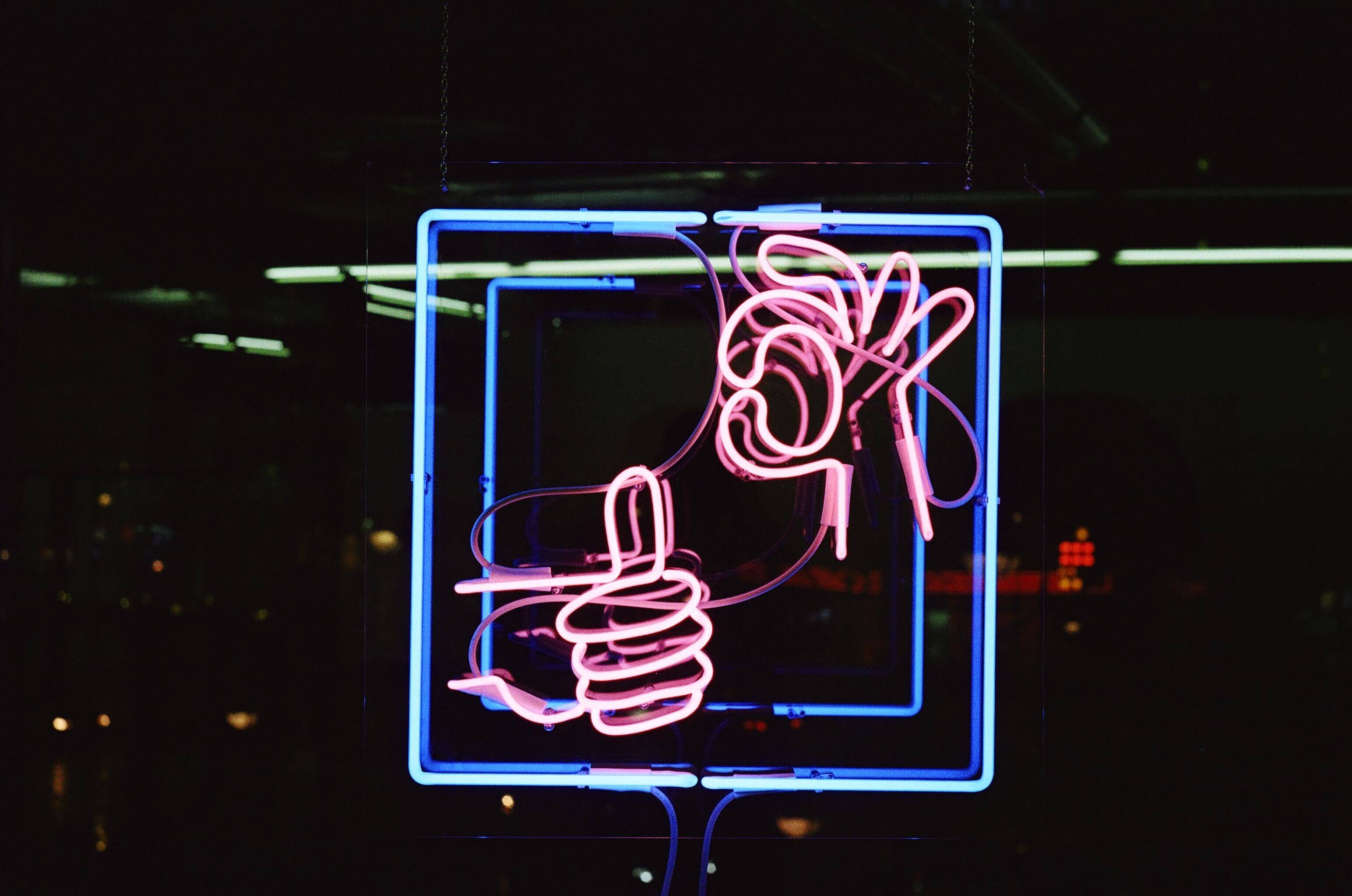 A neon sign showing a thumbs up and an OK sign