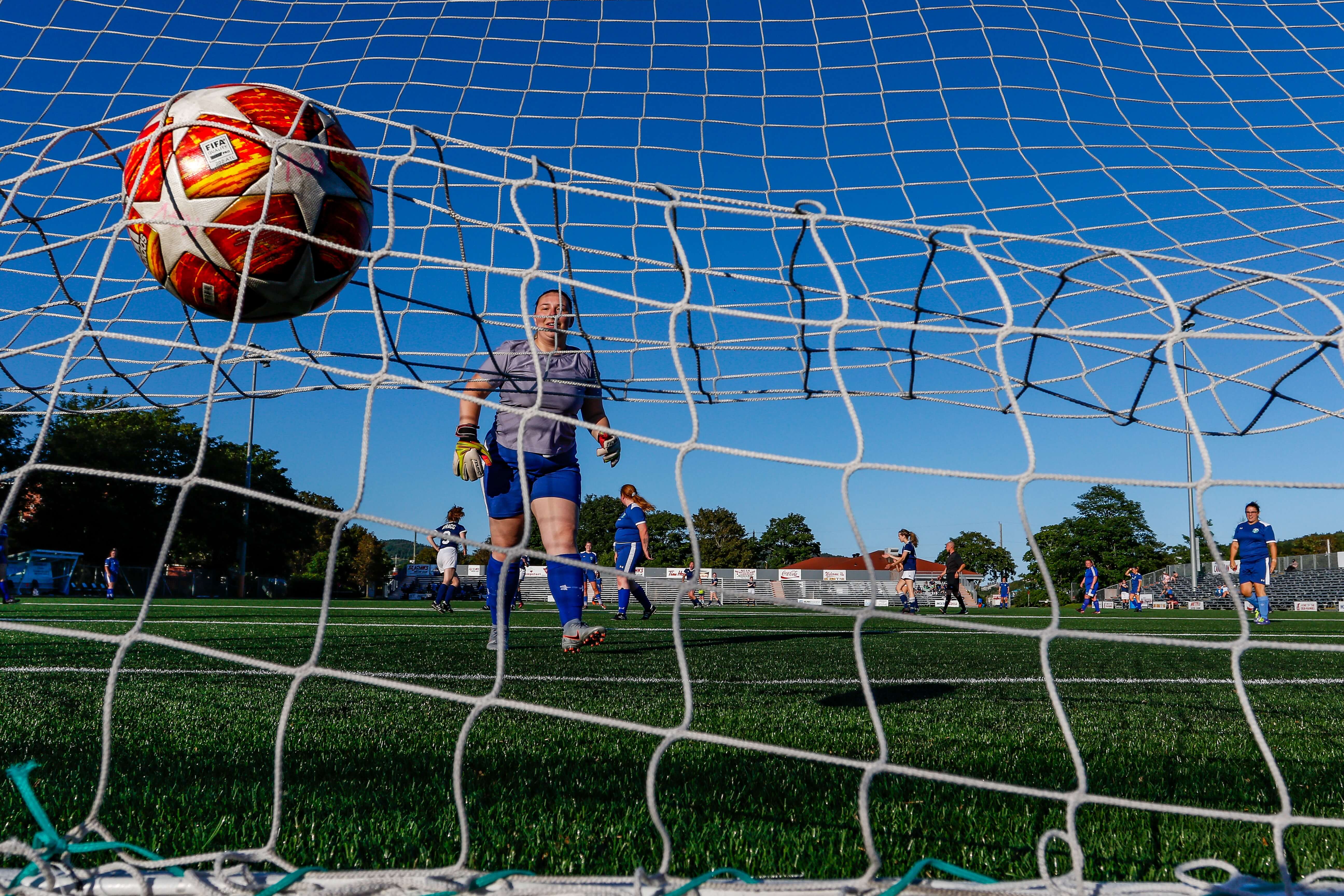 A woman kicks a soccer ball into the goal